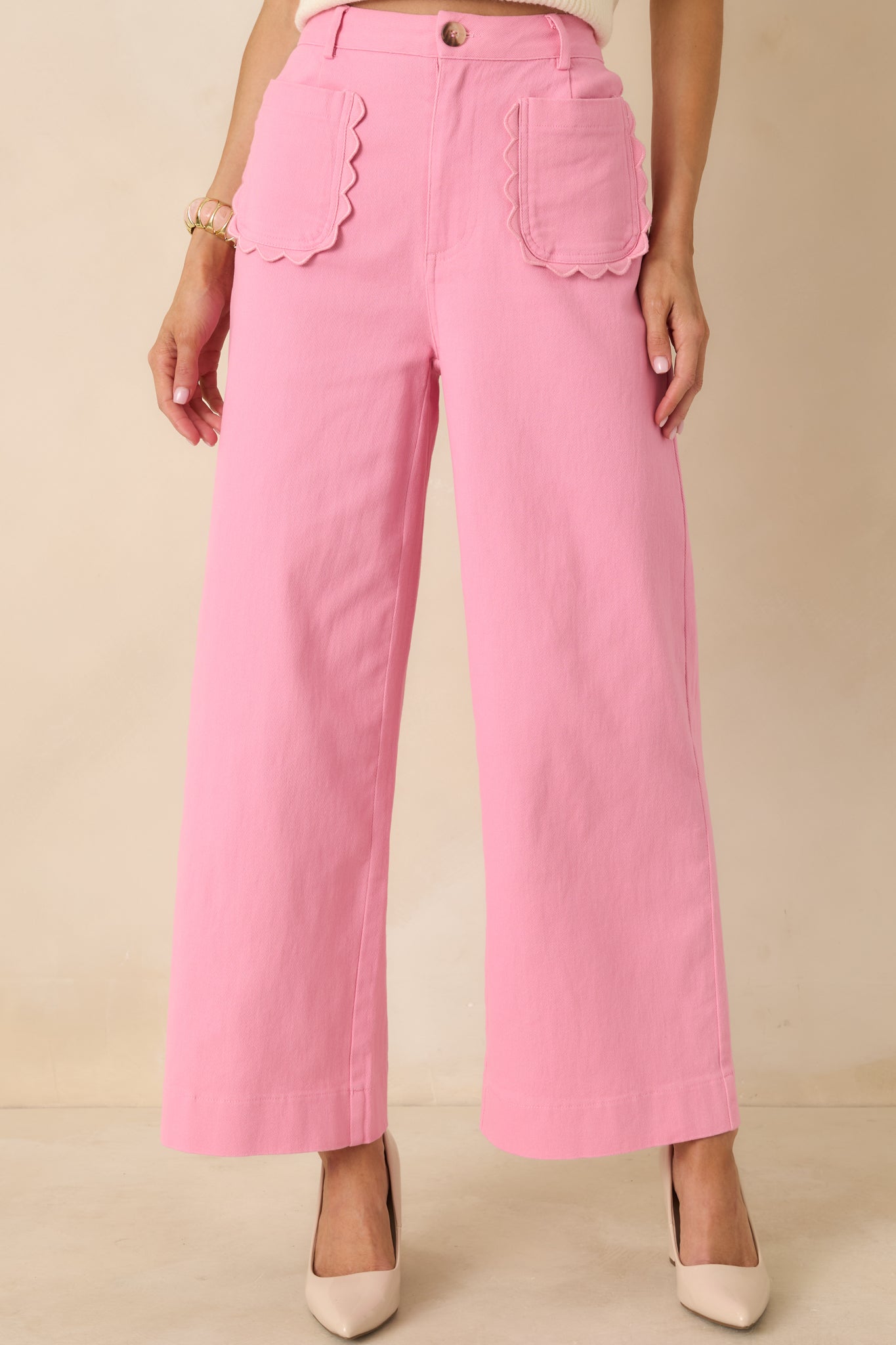 Detail of pink cotton pants highlighting scalloped pocket trim and the soft, structured woven cotton texture.