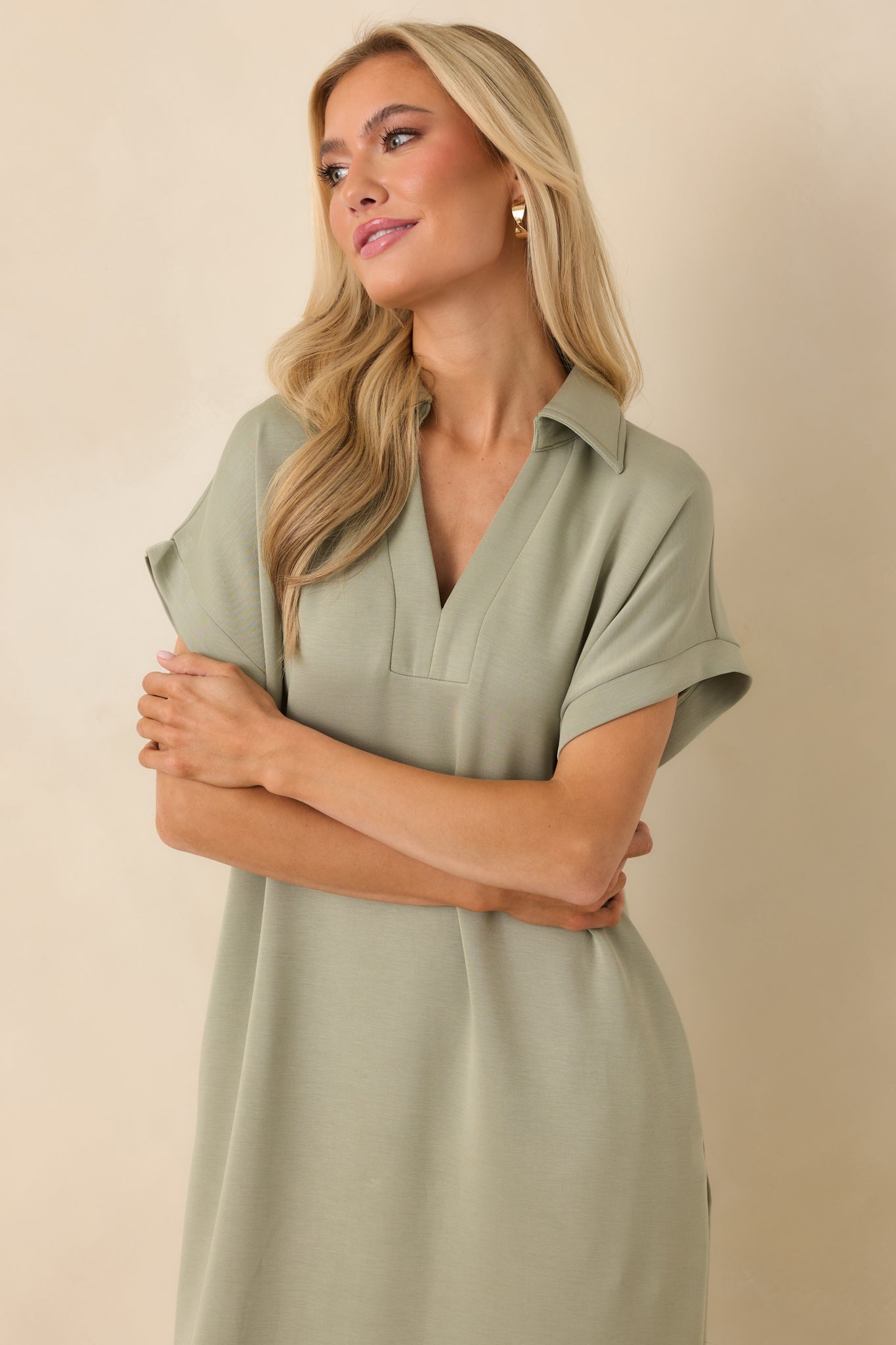 Soft sage green midi dress featuring a structured collar, notch v-neck, functional pockets, and a smooth, draped silhouette.