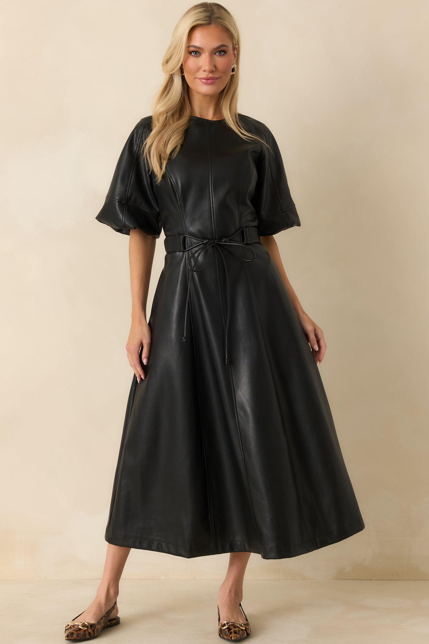 Midi-length faux leather dress showcasing vertical seam lines and a softly structured silhouette.