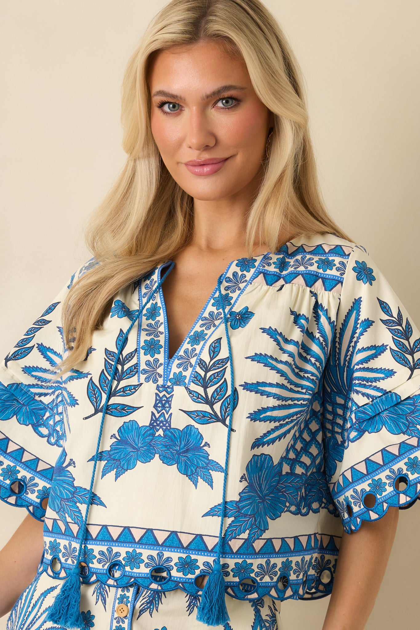 Cropped view emphasizing the V-neckline, tassel accents, and vibrant tropical pattern.