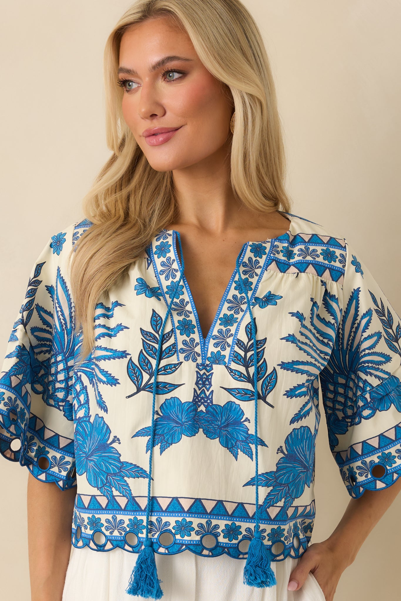 Cropped view highlighting the V-neckline and decorative tassel accents.