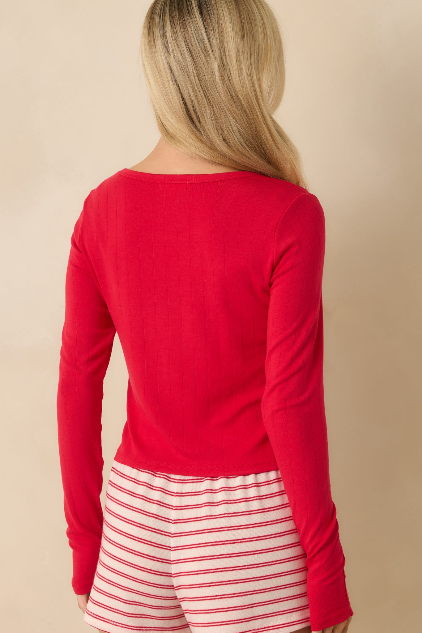 Rear view of the red ribbed knit top showcasing the fitted silhouette and smooth finish
