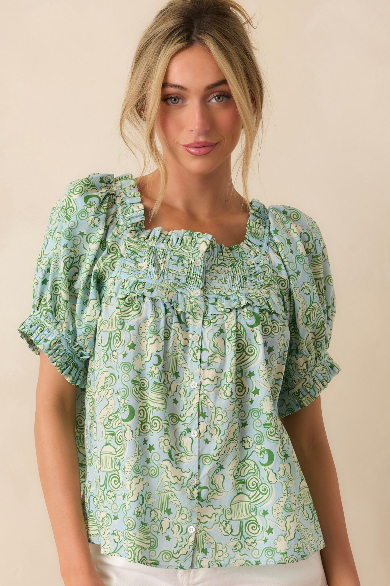 Woman wearing a green patterned blouse against a beige background