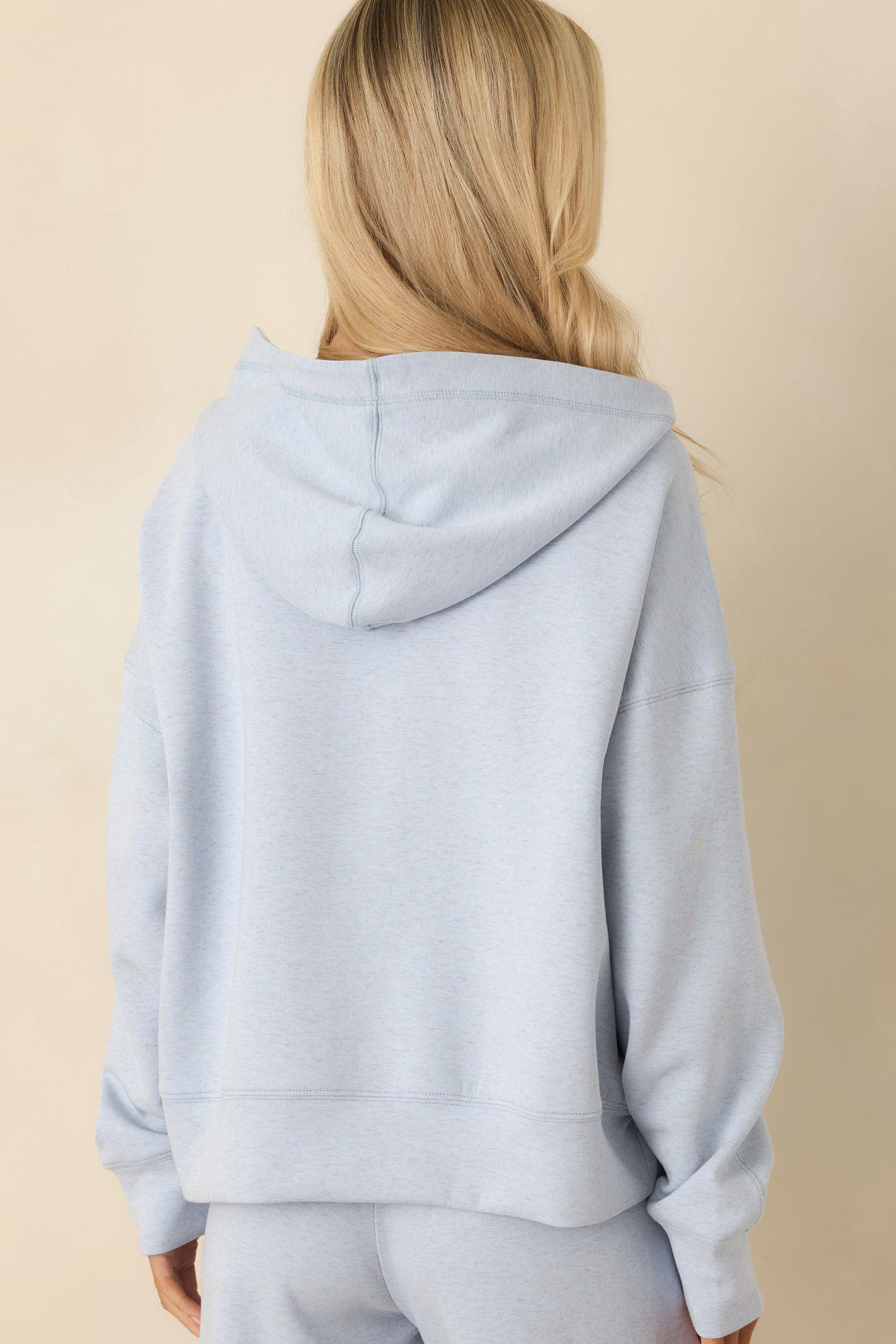 Rear view of light heather blue hoodie, focusing on the hood shape and seam accents.