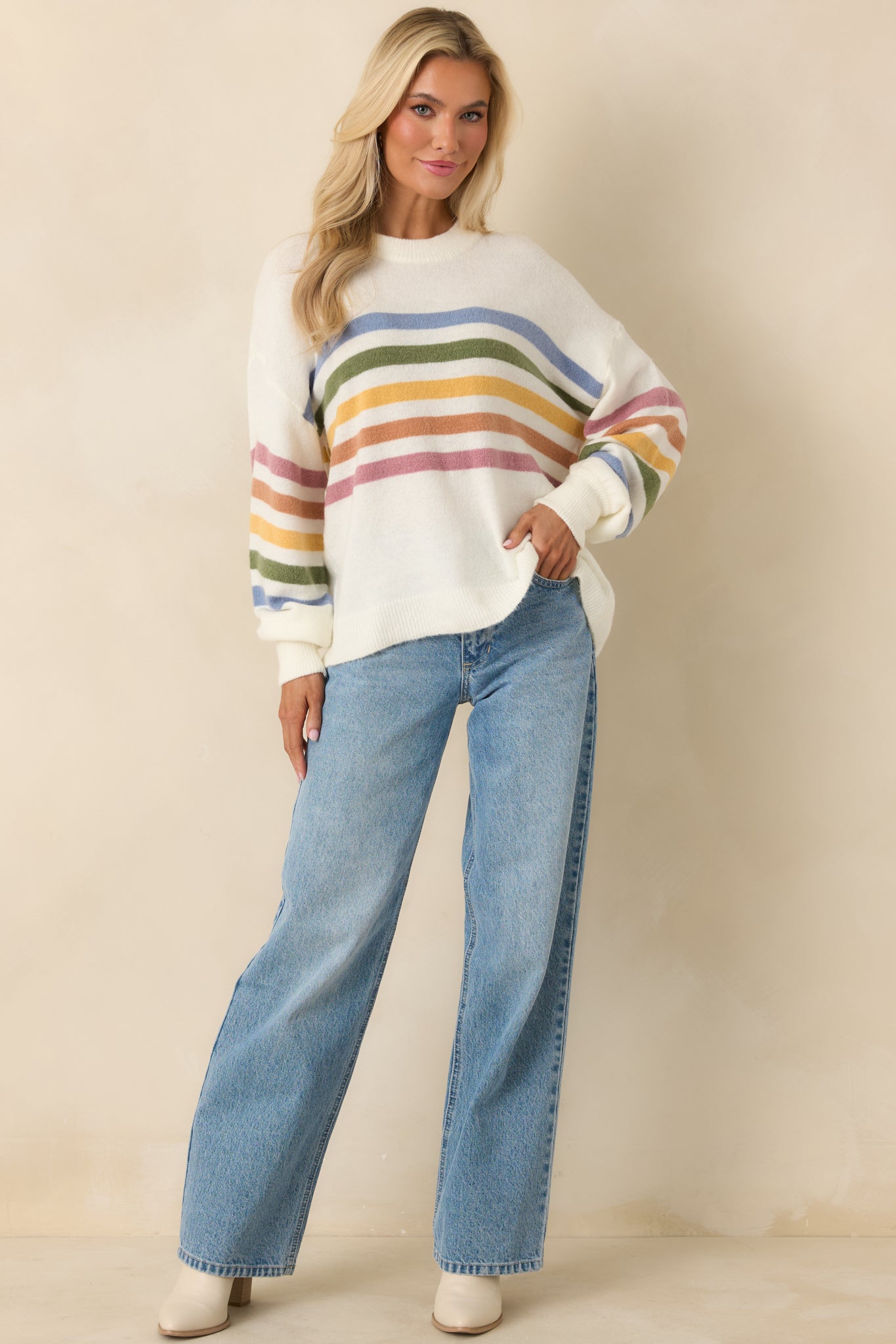 Ivory crewneck knit sweater with multicolor horizontal stripes across chest and sleeves.