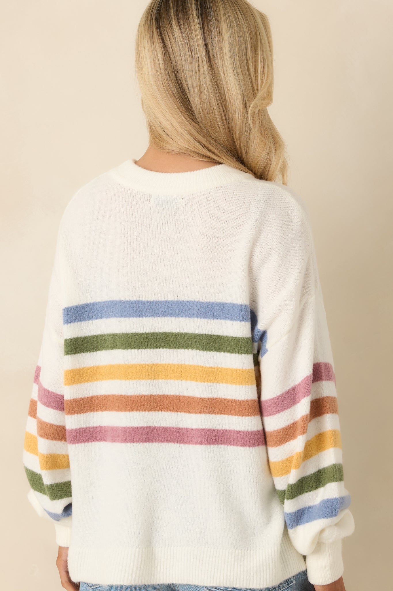 Rear view of ivory knit sweater showing continuous stripe sleeve detail and seam design.