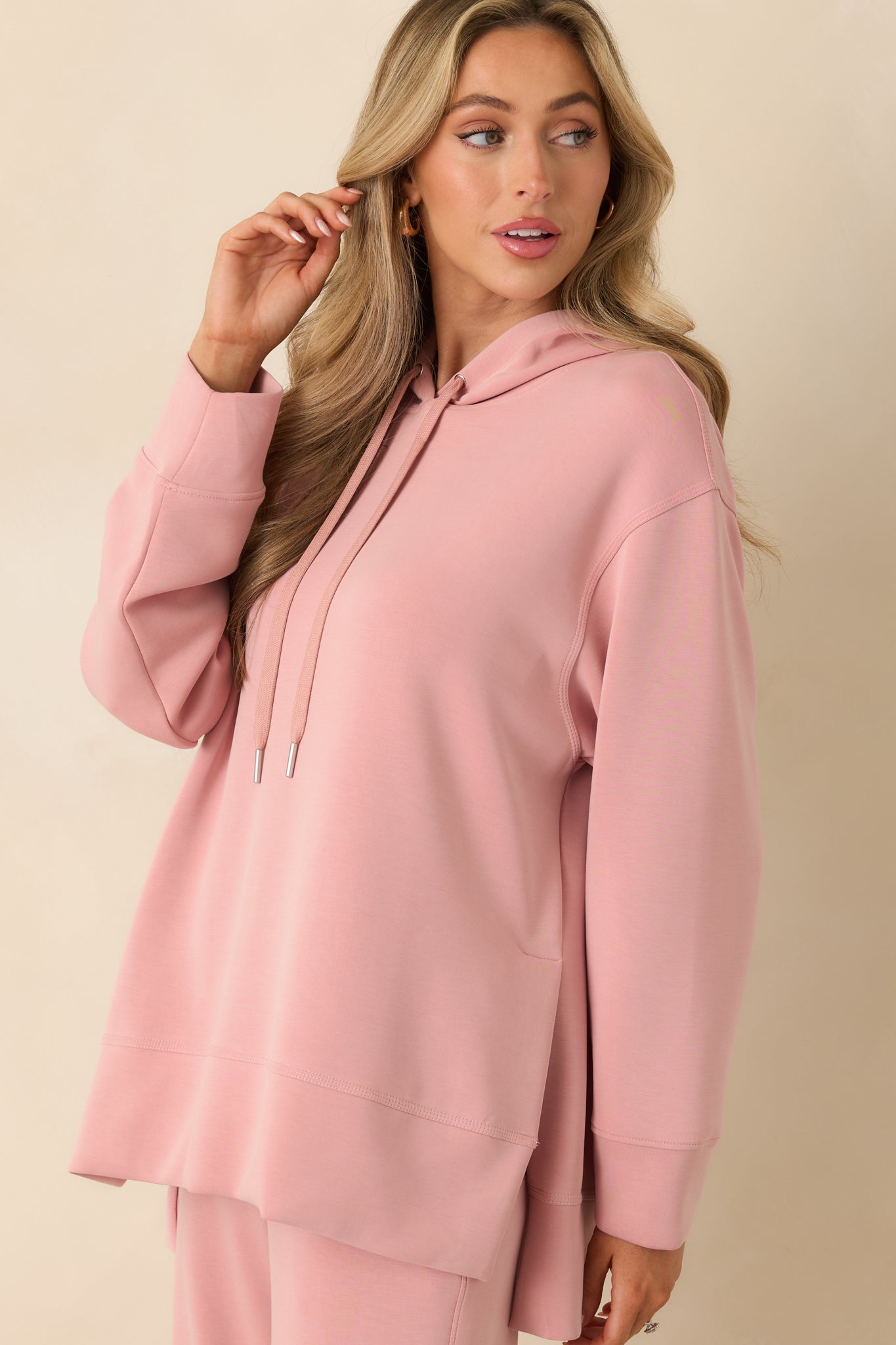 Focused view of dropped shoulder and relaxed fit on pink sweatshirt.