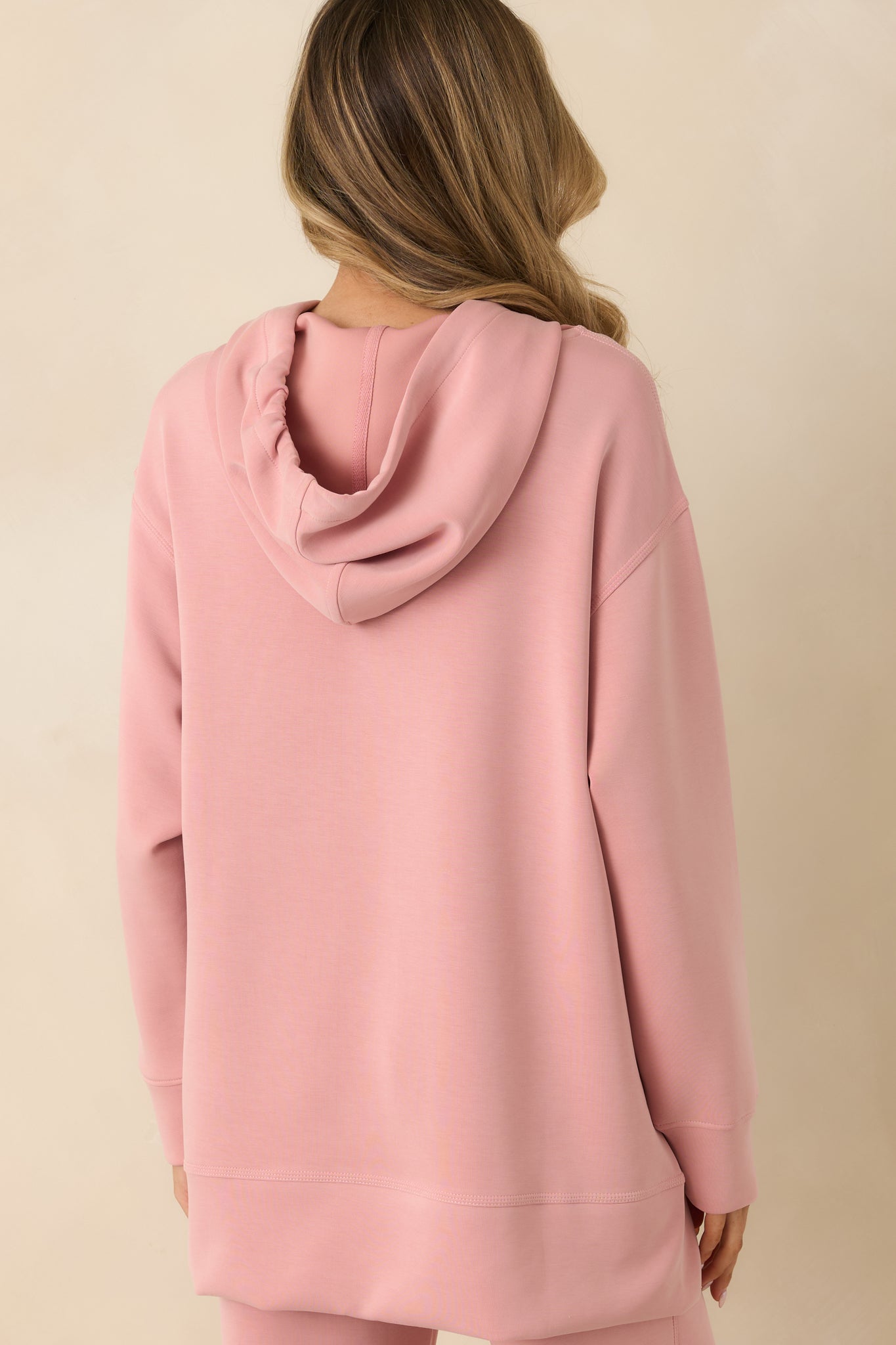 Rear view of powder pink sweatshirt showing attached hood and relaxed fit.