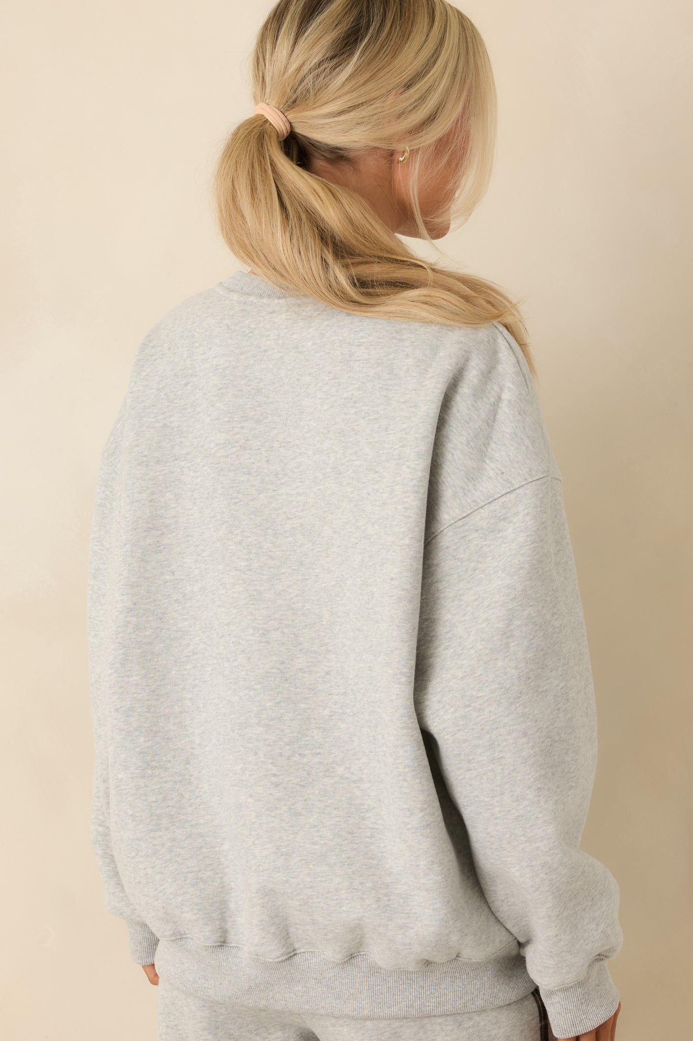Rear view of heather grey sweatshirt showing relaxed fit and ribbed hem and cuffs.
