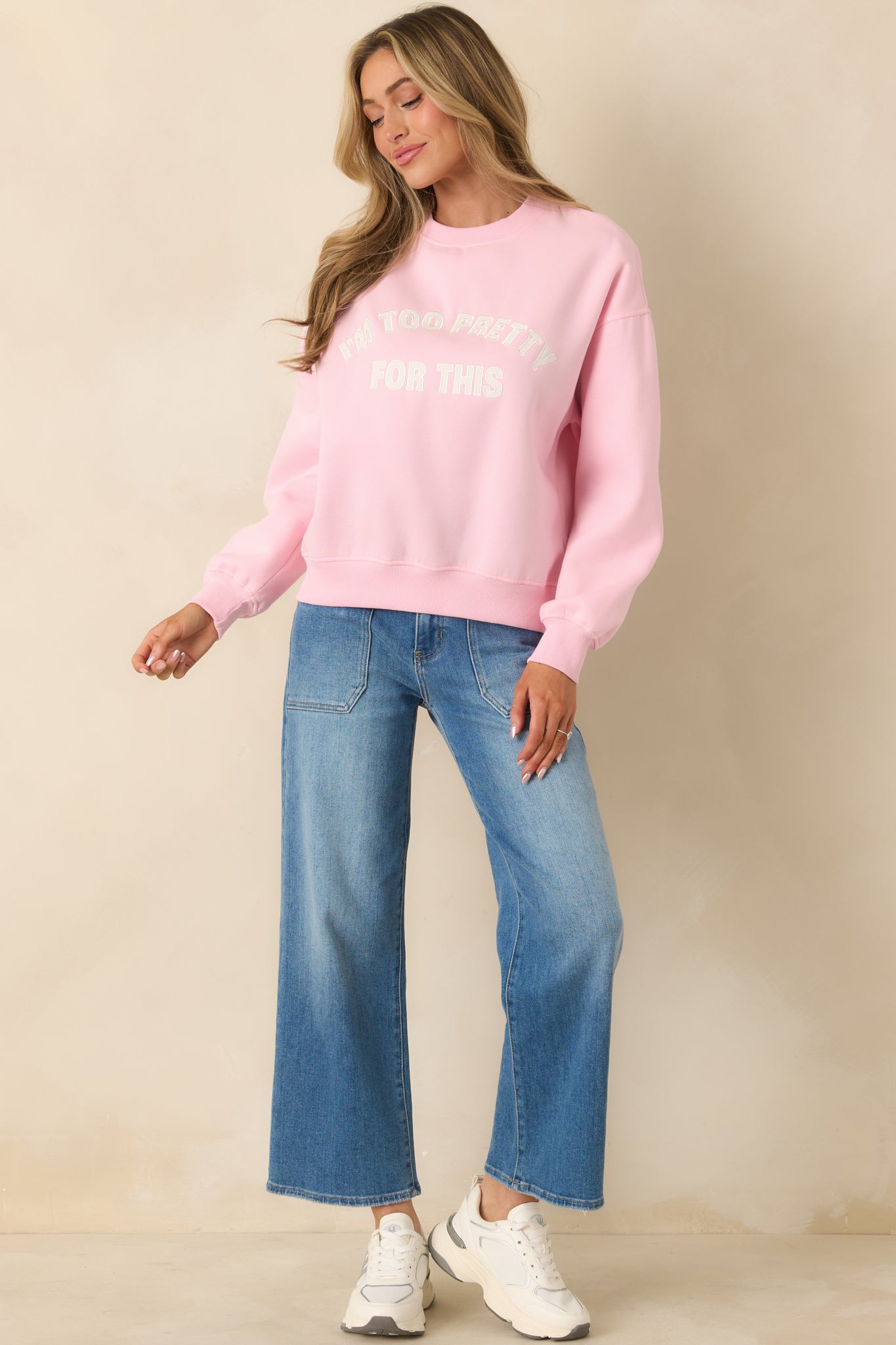 Soft pink sweatshirt featuring ribbed neckline trim and bold embroidered statement detail.