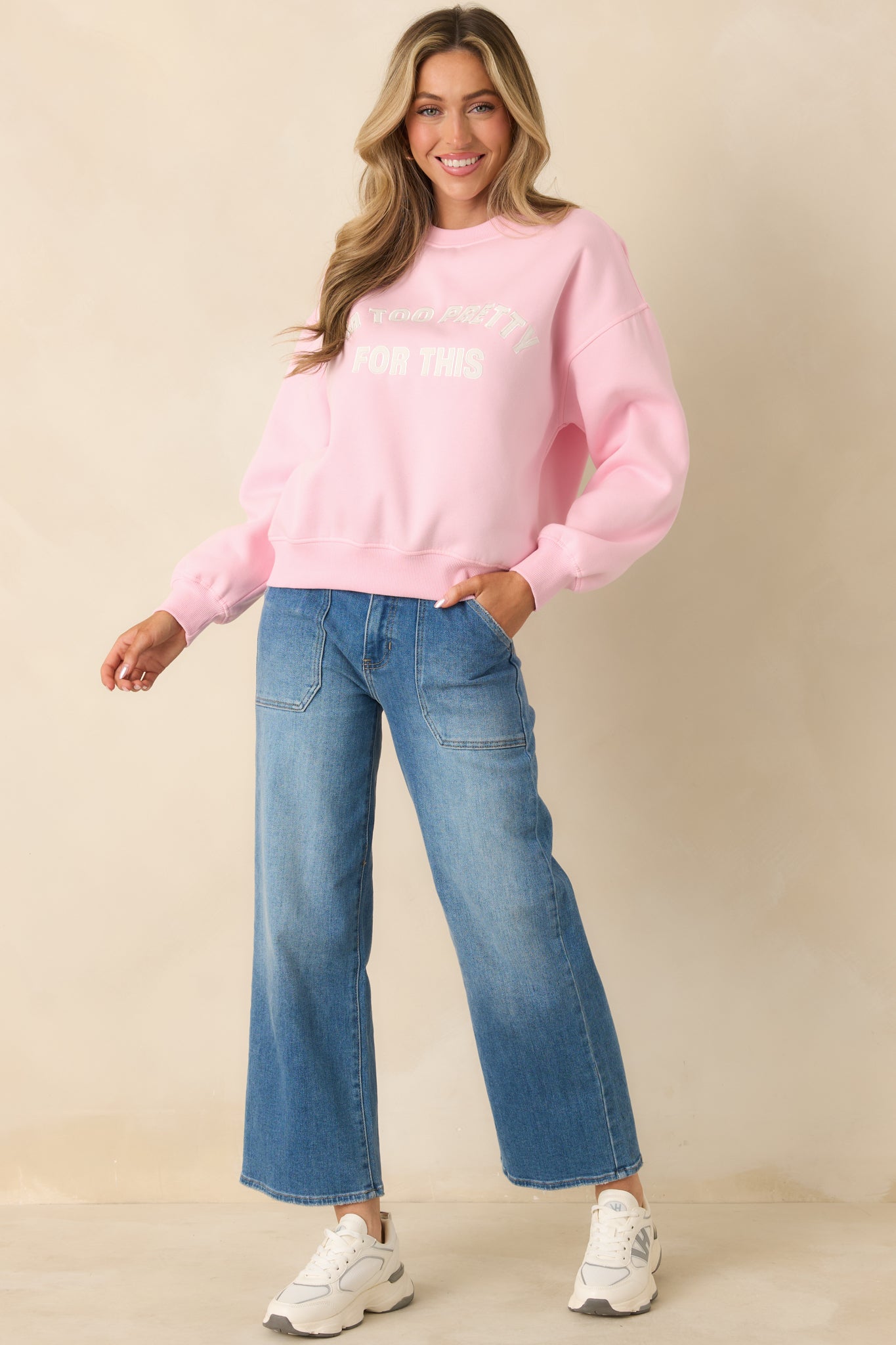 Relaxed pink knit sweatshirt with ribbed cuffs and embroidered text centered on the front.
