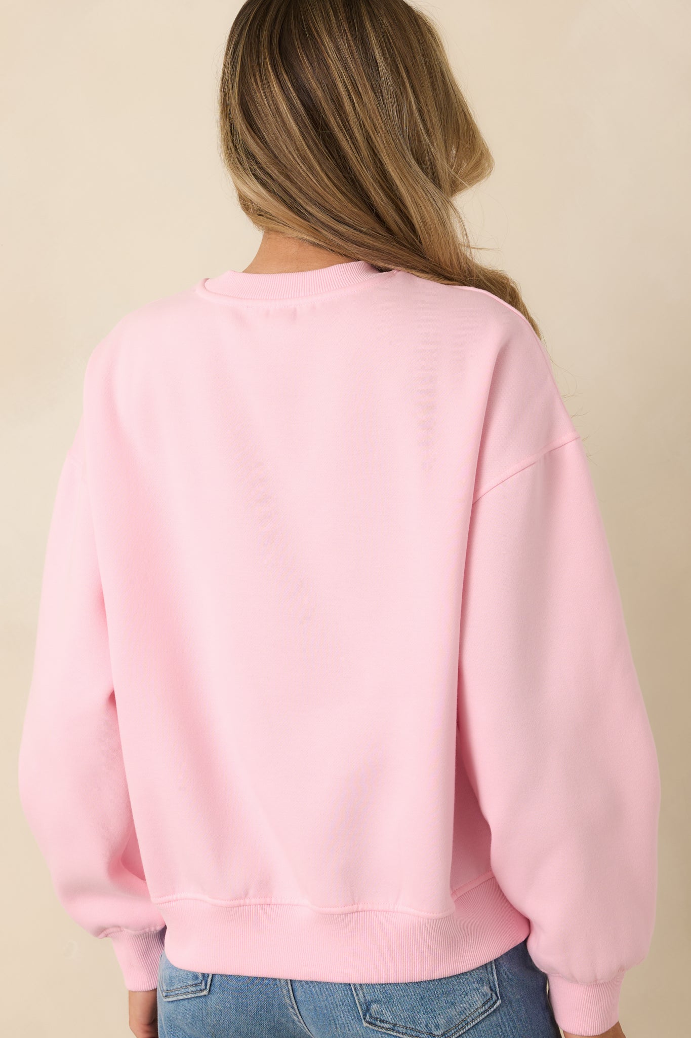 Rear view of pink sweatshirt showing smooth fabric and clean seam layout.