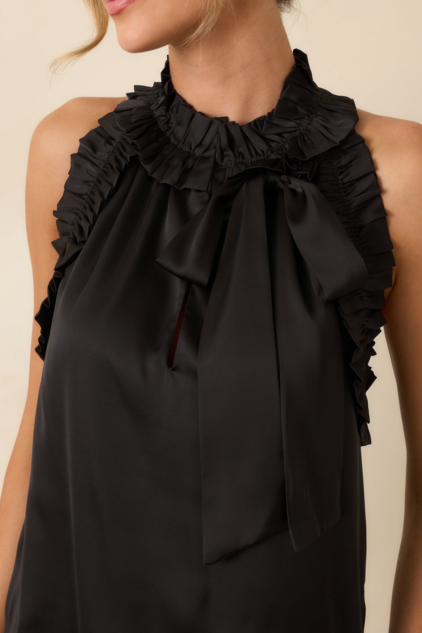 Close-up detail of the black top highlighting the ruffled edges, self-tie bow, and lightweight fabric texture.