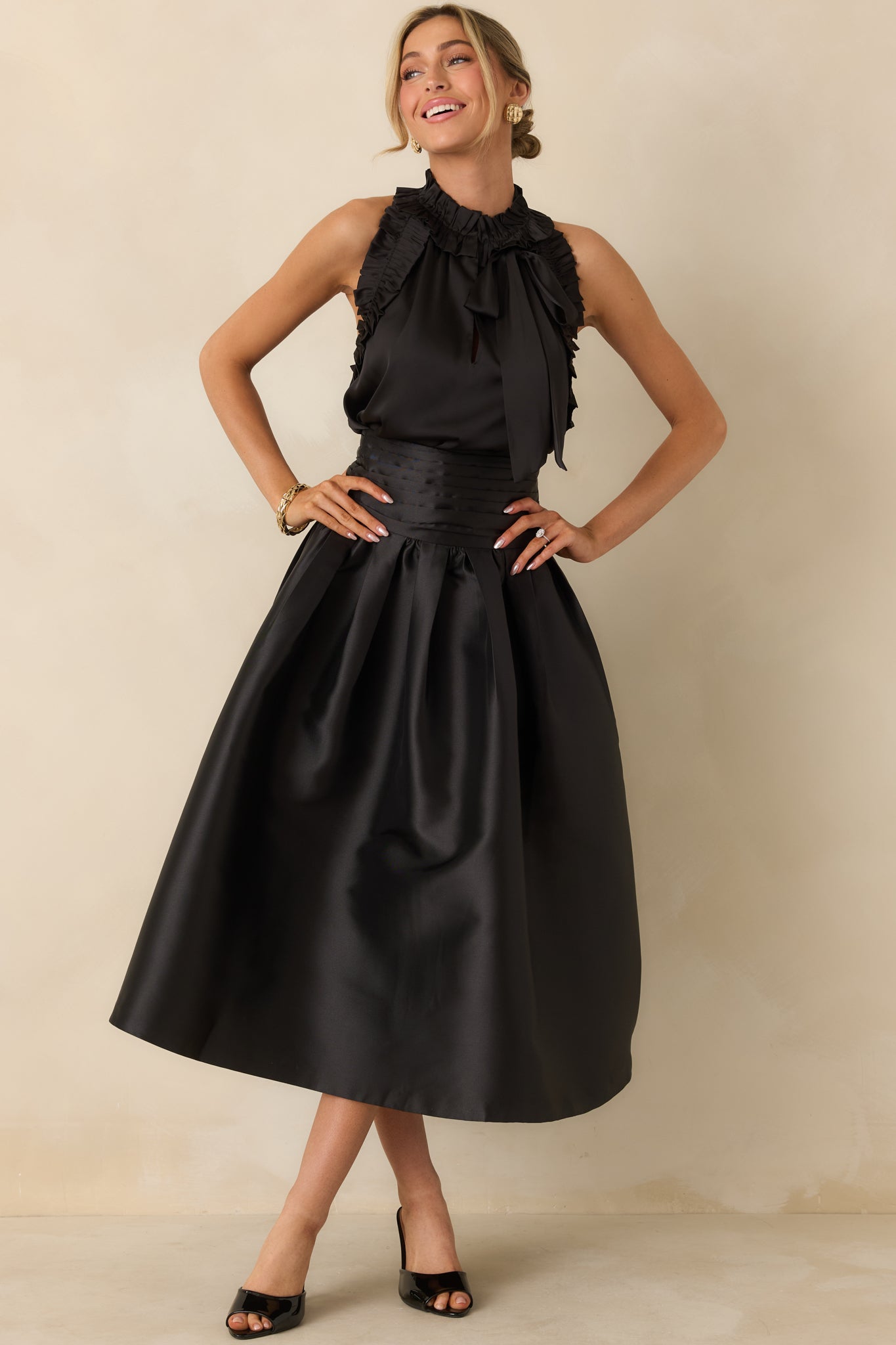 Black sleeveless top with a high ruffled neckline, ruffle trim along shoulders, and relaxed silhouette.