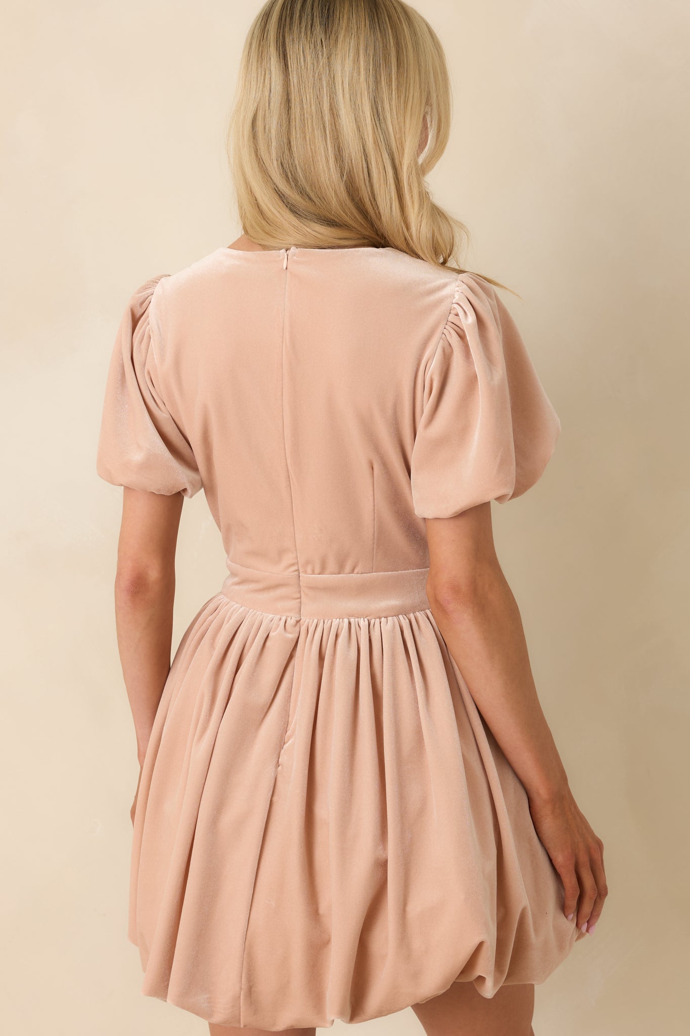 Rear view of blush pink velvet mini dress with a clean lined finish and soft waist shaping.