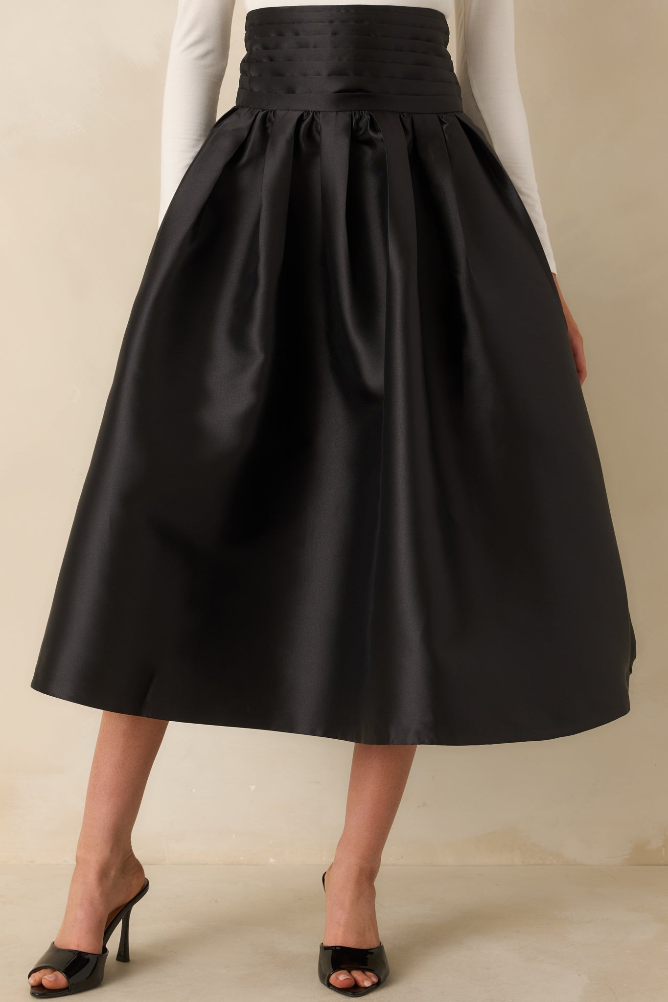 Black skirt with a flowing A-line silhouette and pleated detailing displayed from a full-length angle.