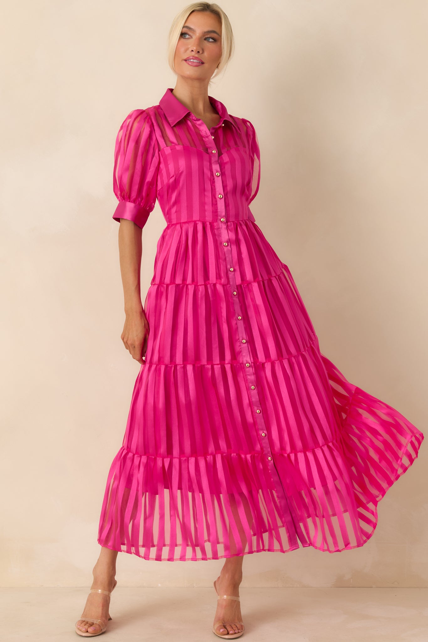 Fuchsia pink maxi dress with a collared neckline, short puff sleeves, and functional button-up front on a fitted bodice.