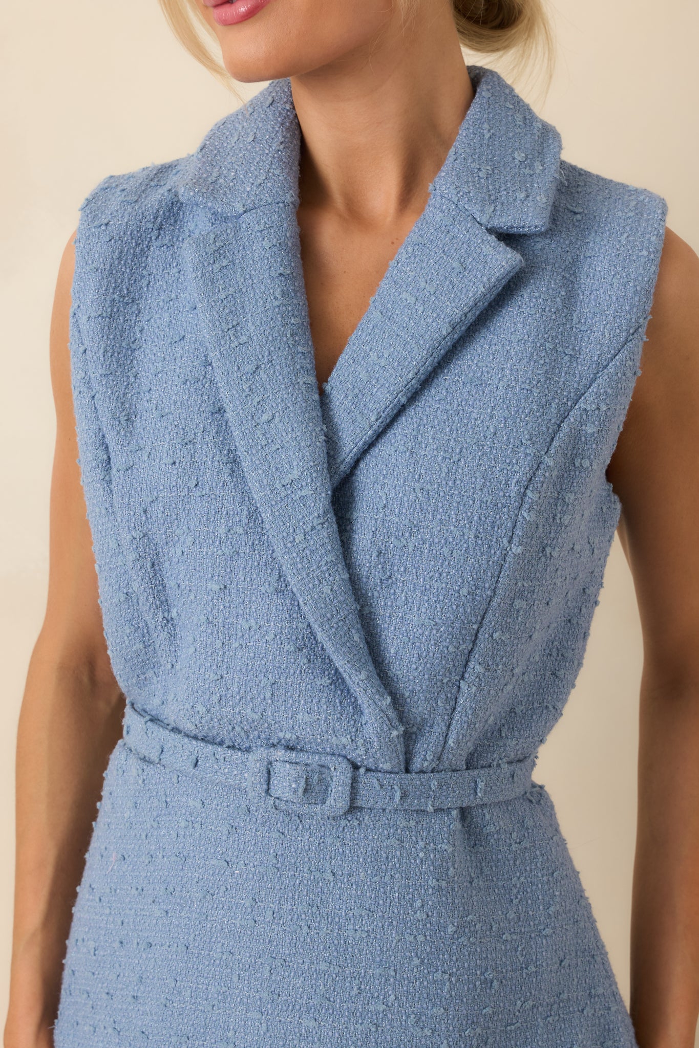 Close view of textured woven bodice and pleated lace skirt, highlighting fabric texture and waist belt.