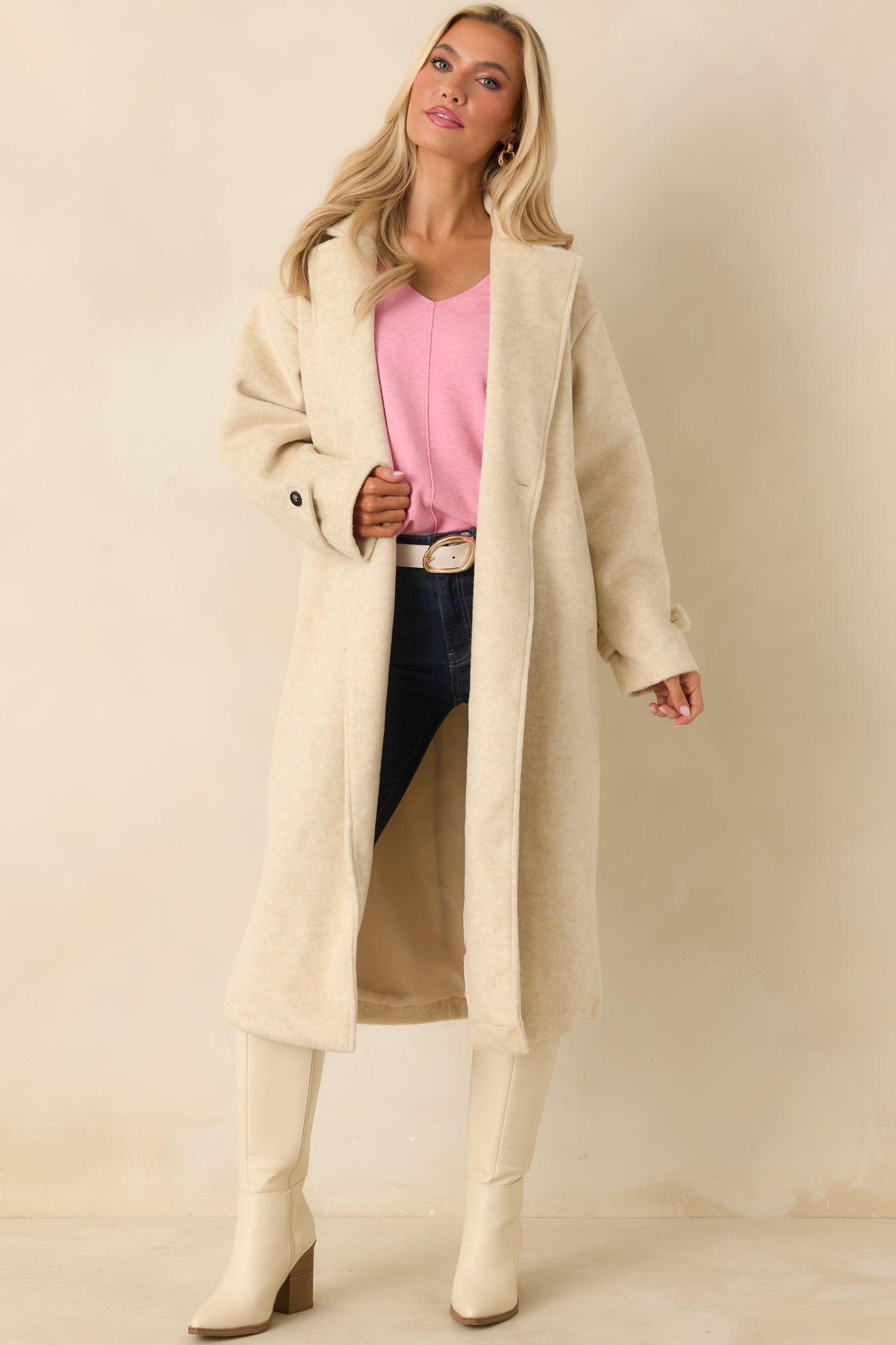 Longline ivory coat with an open collar, double-breasted front, and soft wool-blend texture creating a polished silhouette.