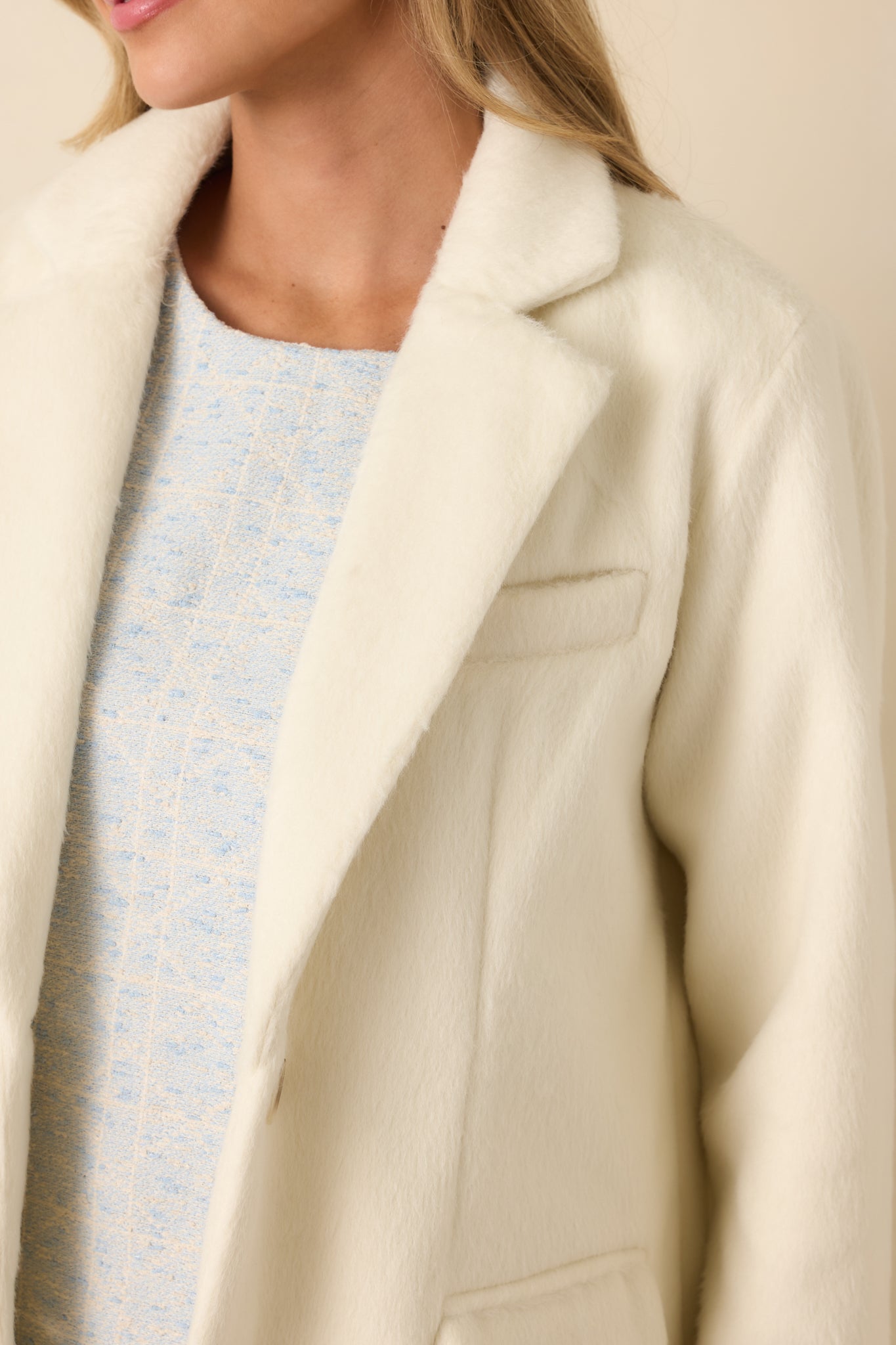 Tight detail of the lapel stitching and dense felted texture in soft ivory.