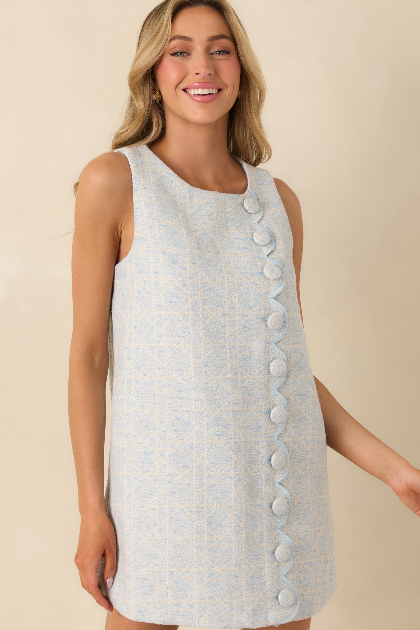 Decorative fabric-covered buttons on the front of a light blue woven mini dress.
