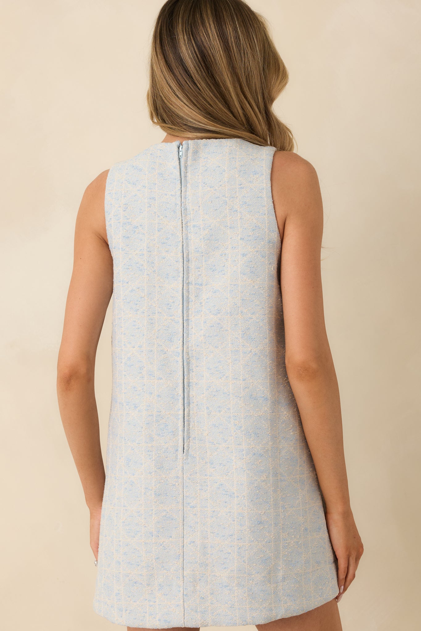 Rear view of a light blue mini dress with textured woven geometric pattern, sleeveless silhouette, and concealed zipper closure.