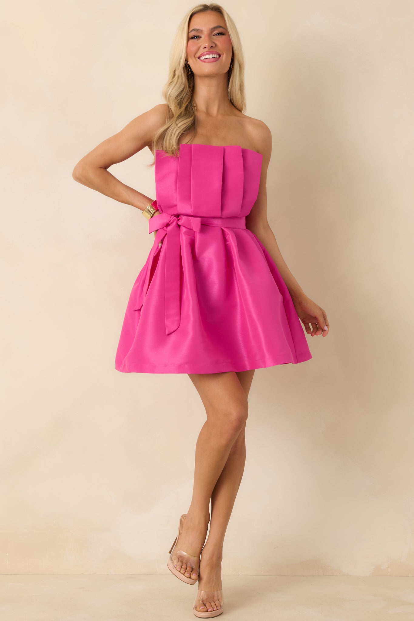 Fuchsia mini dress with pleated detailing along the bodice, a fitted waist, and gently flared skirt for movement.
