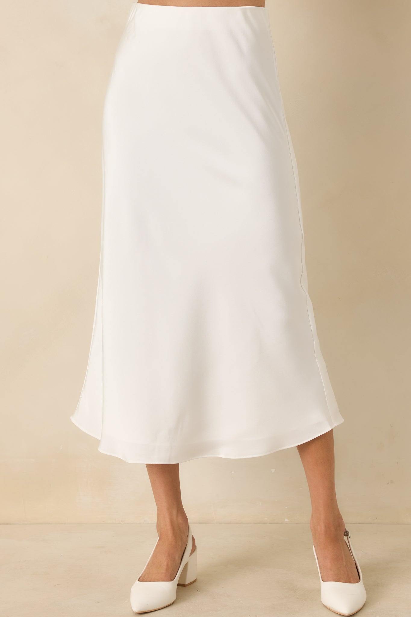 Close view of the white midi skirt fabric highlighting the satin-like texture and soft, flowing flare.