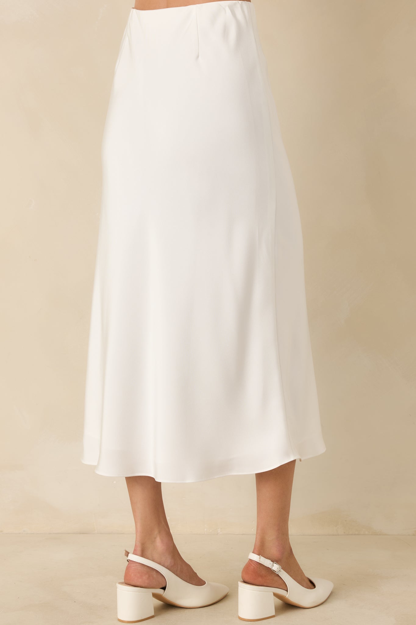 Rear view of the white midi skirt showing a gently flared silhouette, full lining, and smooth, polished finish.