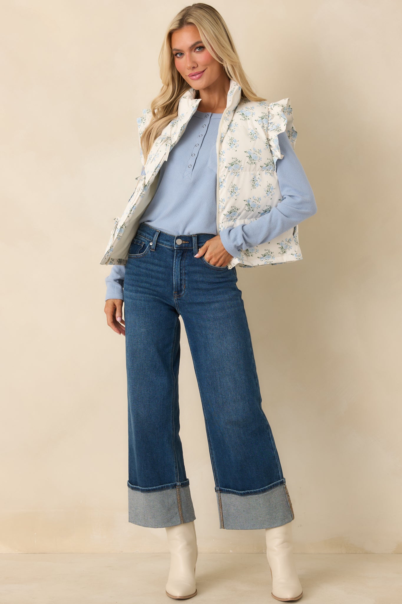Ivory puffer vest with allover blue floral pattern, lightly padded quilted construction, stand collar, and front self-tie closures.