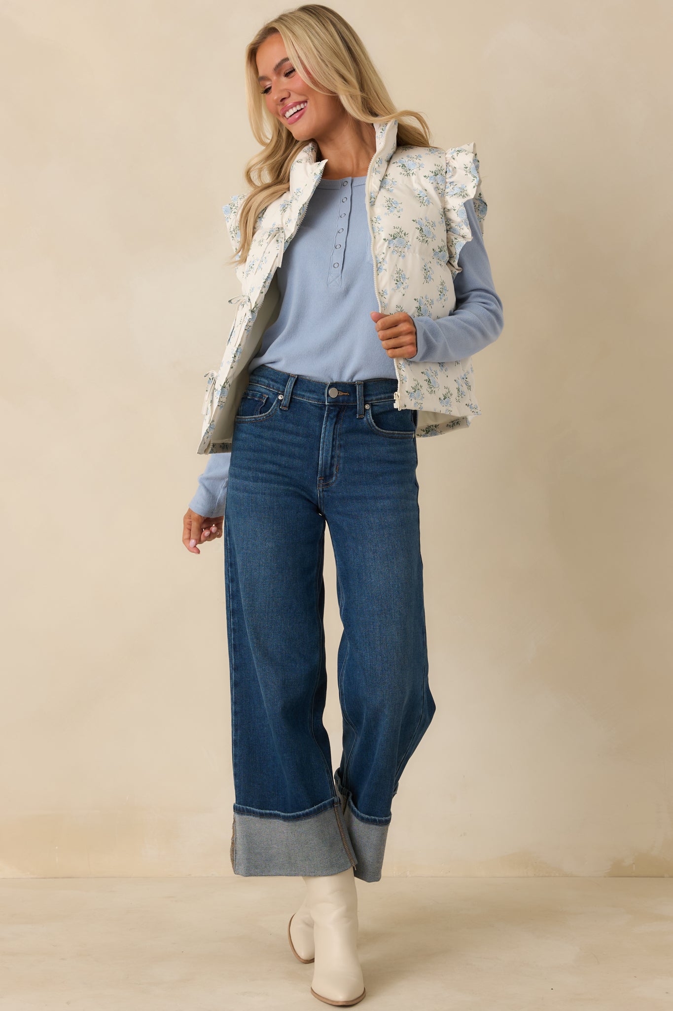 Ivory puffer vest with blue floral quilting, stand collar, front self-ties, and gently structured, lightweight padding.