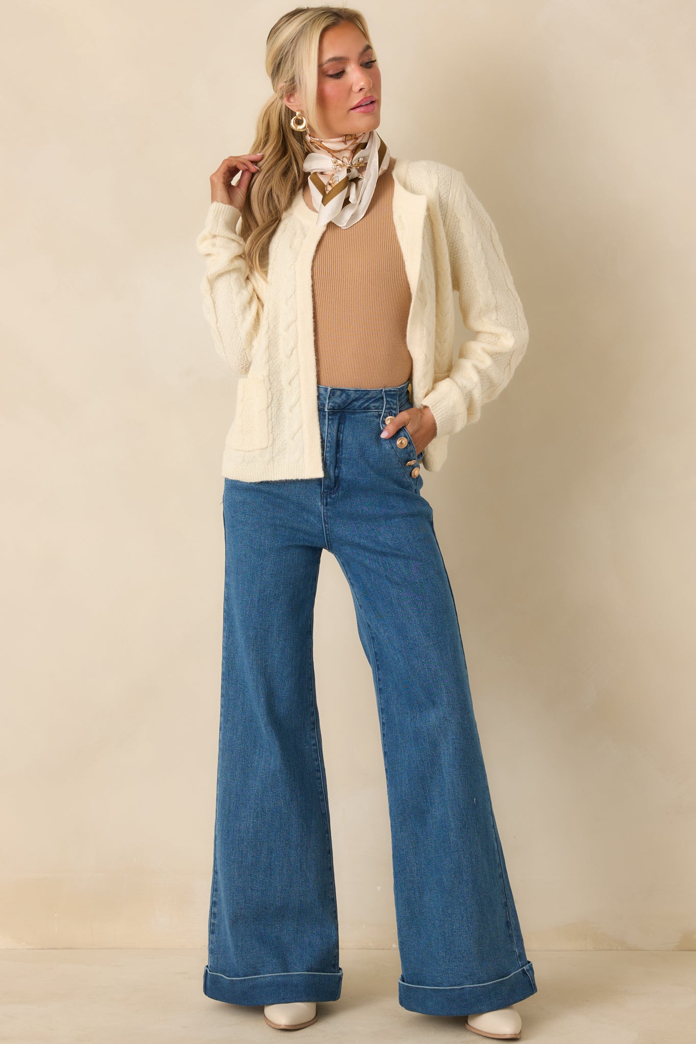 Ivory cable knit cardigan with open-front design, long sleeves, front patch pockets, and ribbed trim at cuffs and hem.