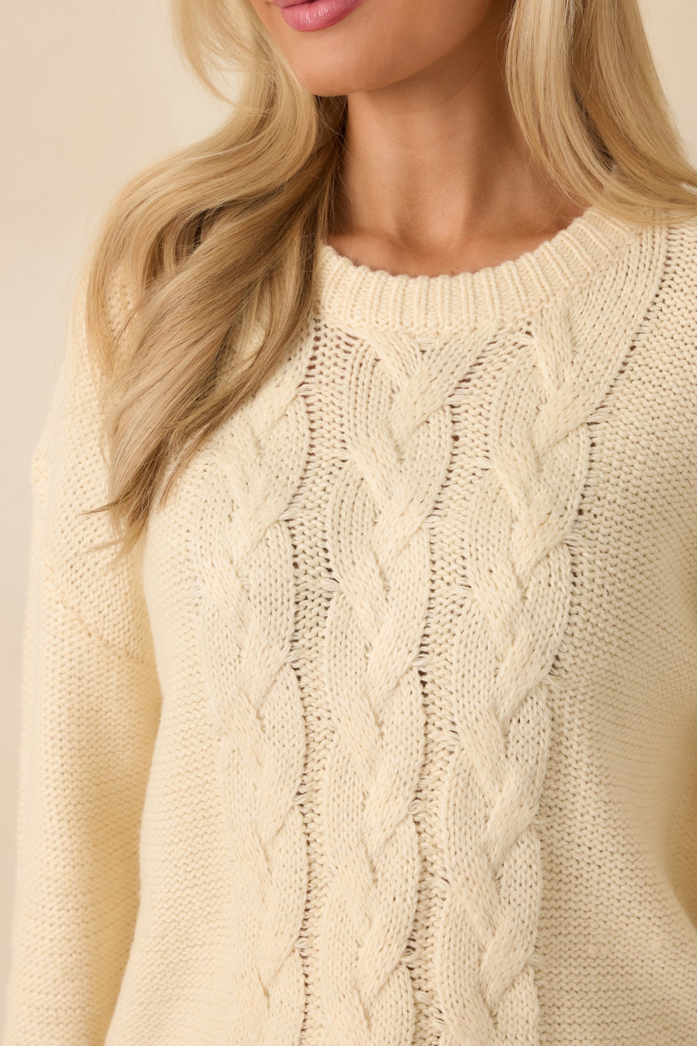 Ultra close knit view of the cable stitch pattern showing the soft ivory yarn and textured knit dimension.