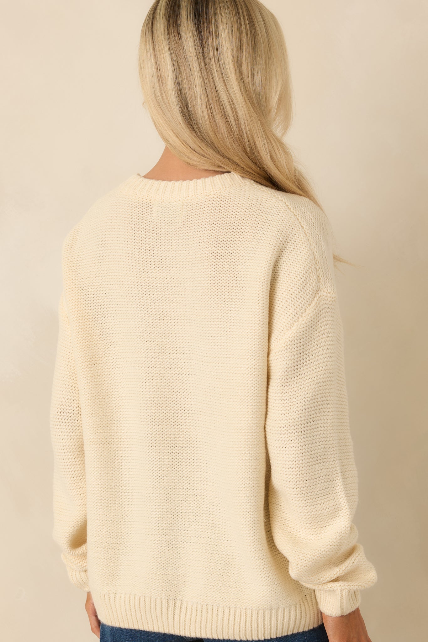 Rear photo of the ivory knit sweater featuring a smooth knit finish and structured ribbed hem for subtle shape retention.