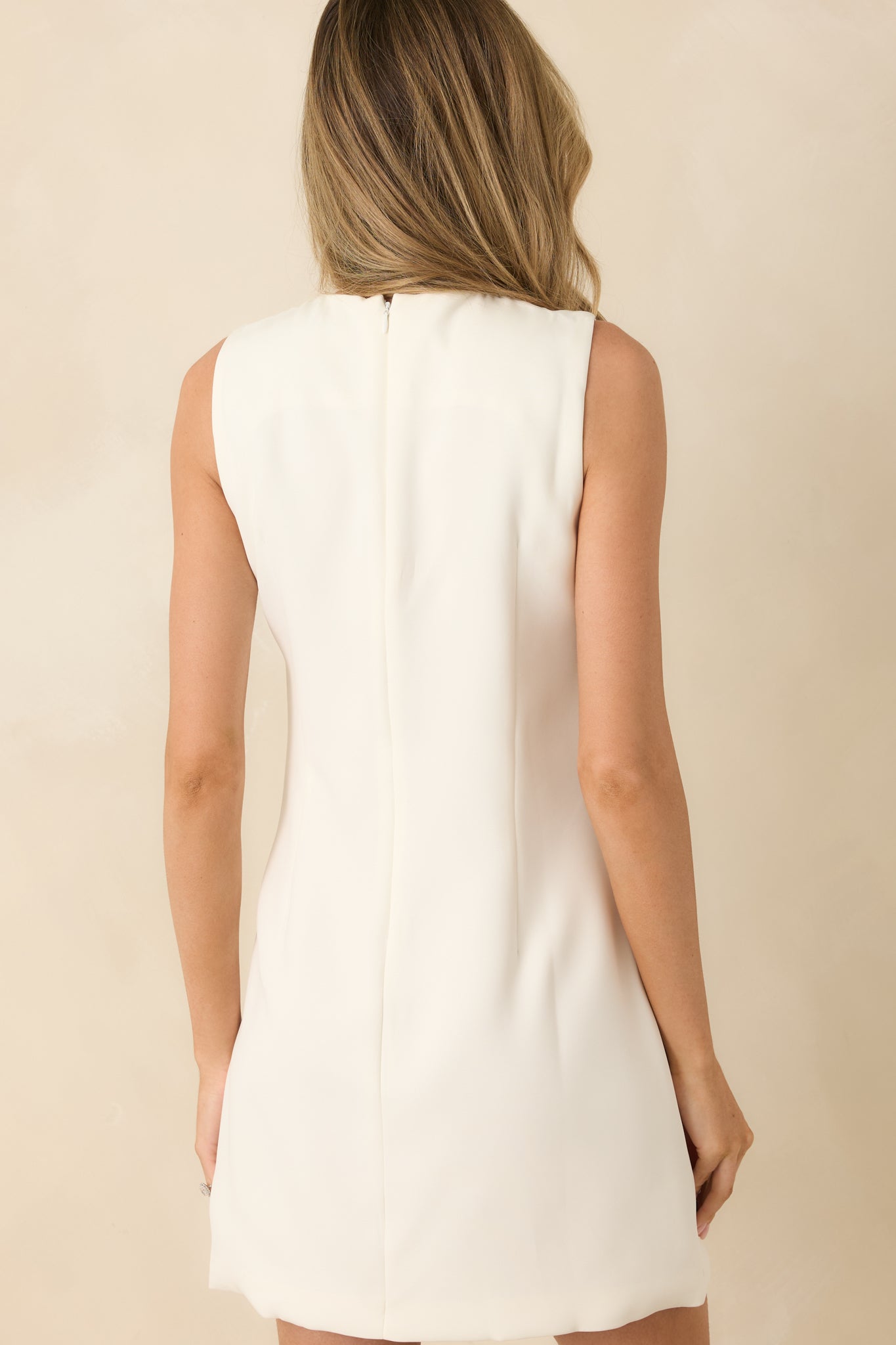 Rear view of ivory mini dress with a hidden zipper closure and a clean, woven fabric finish.