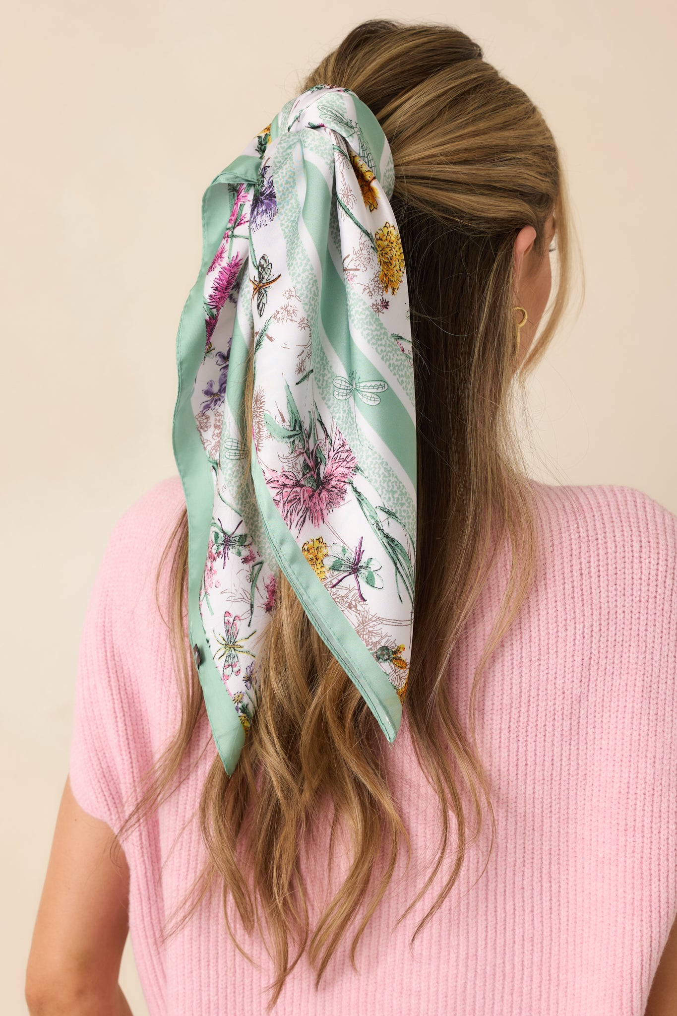 Close-up of white scarf showing lightweight silky fabric, floral details, and finished green edging.