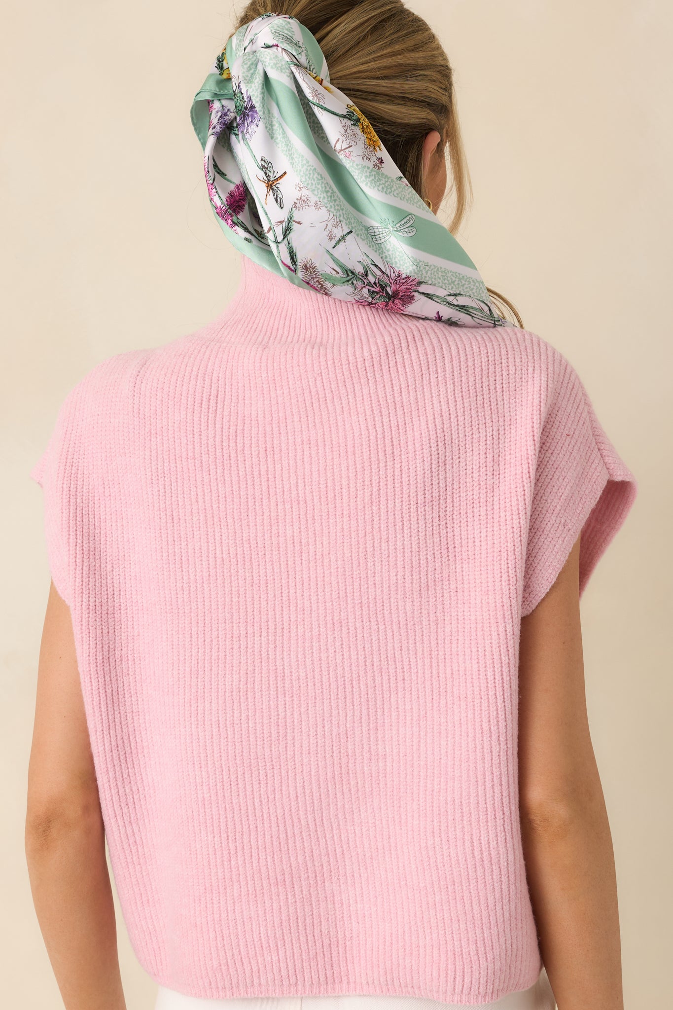 Close cropped section of white scarf showing multi-color floral pattern and subtle green border.