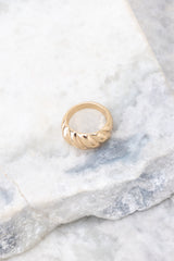 Gold ring that features gold hardware and a ribbed design compared to quarter for actual size. Ring measures .75