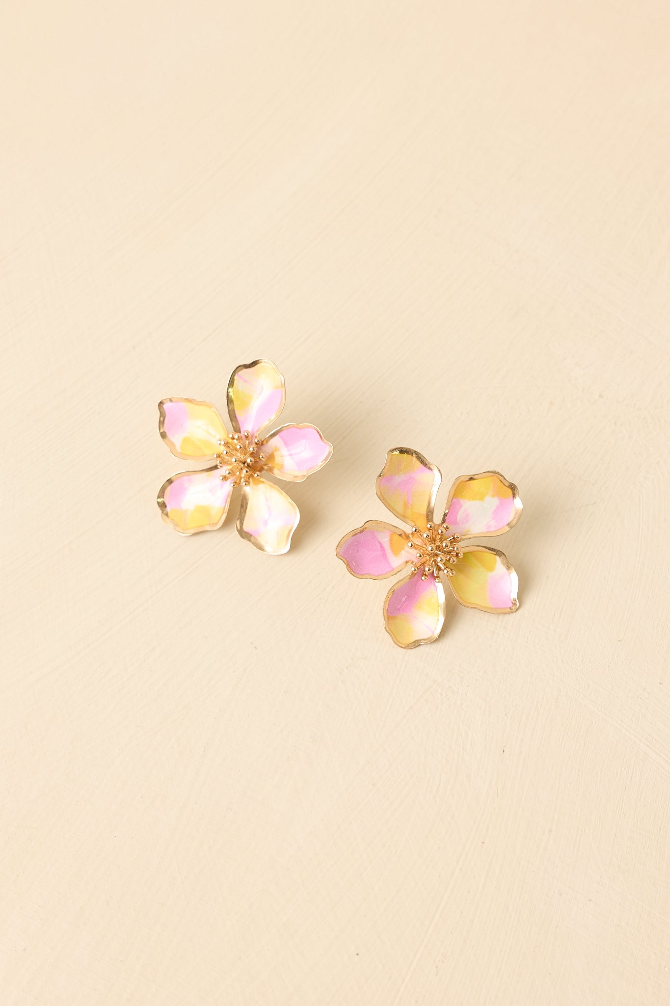 Front view of pink and yellow floral earrings displayed on beige background emphasizing oversized shape.