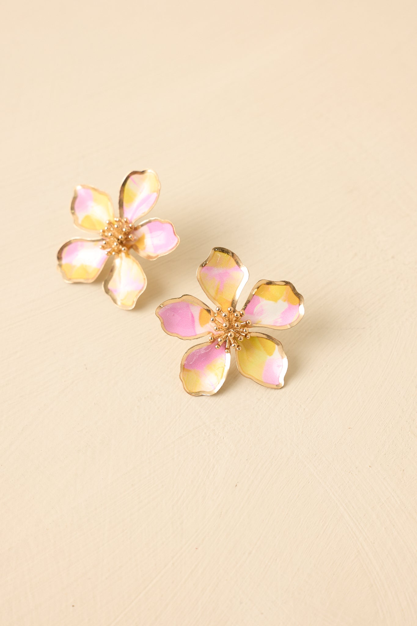 Close-up detail of earrings showing sculpted petals, textured center, and glossy pink yellow finish.