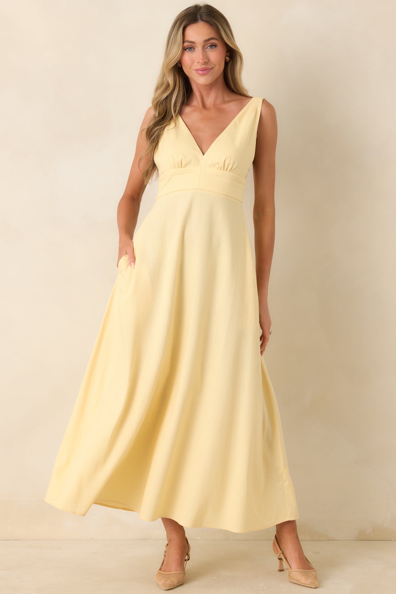 Deep V-neck midi dress featuring a structured waistband, wide shoulder straps, and a full, flowing skirt with a polished, effortless silhouette.