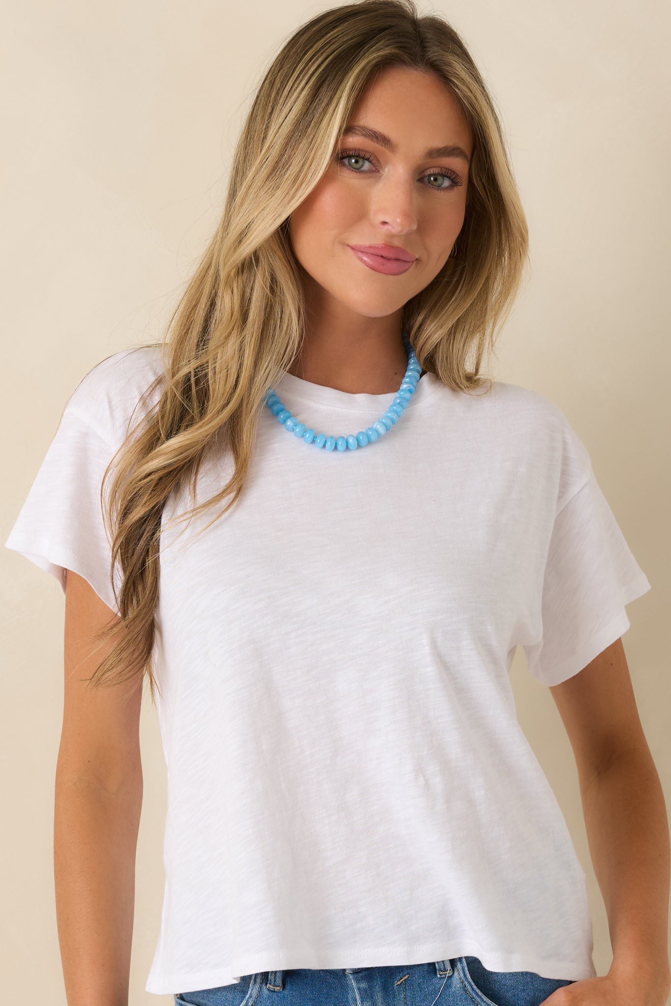 Detailed view of white tee focusing on its soft drape and easy, relaxed fit through the body.