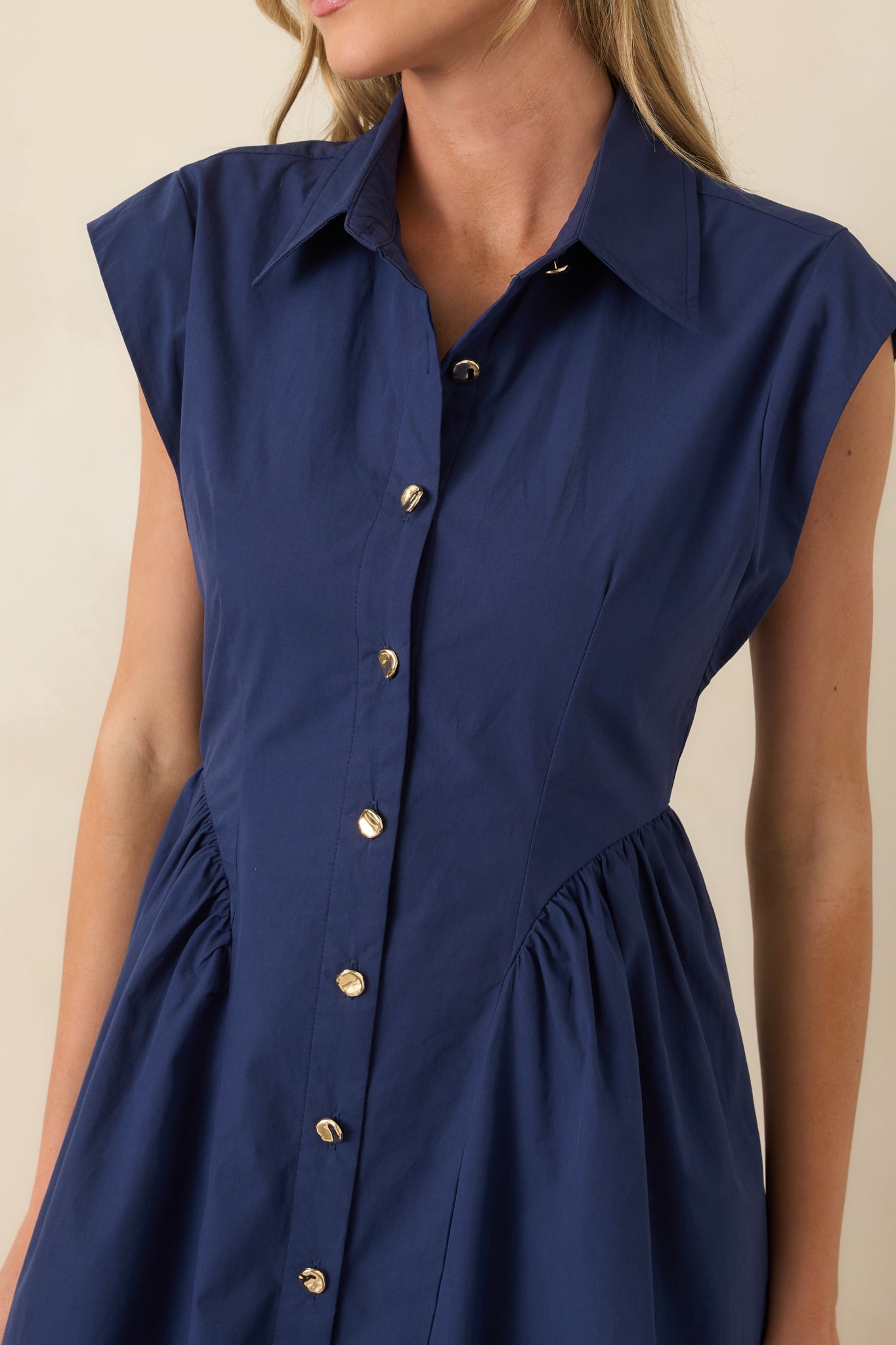 Detailed view of gold button front closure and tailored bodice seaming on navy cotton midi dress.