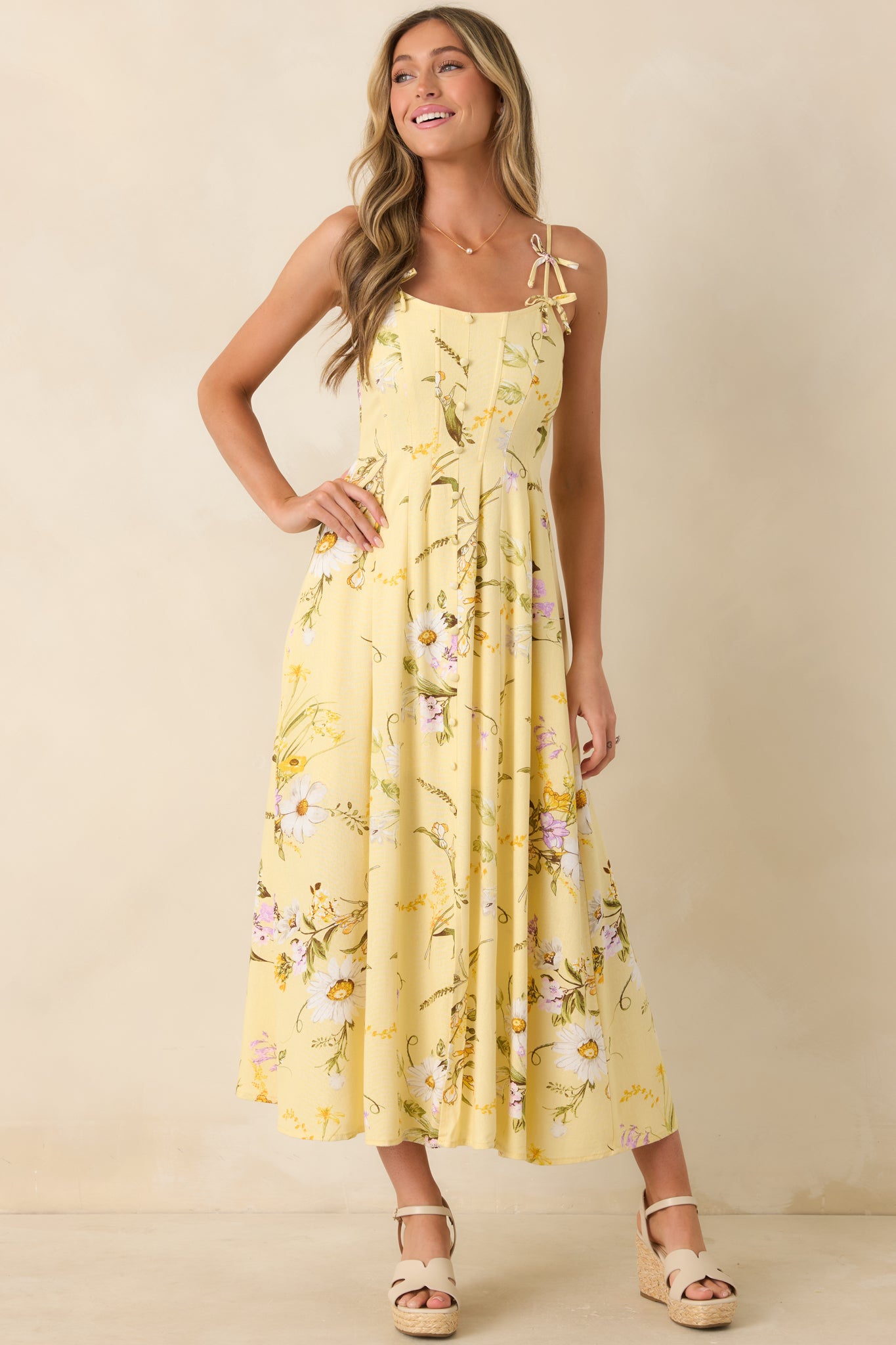 Yellow floral midi dress with delicate bow strap details, tailored bodice seams, and a lightweight, gently flared hemline.