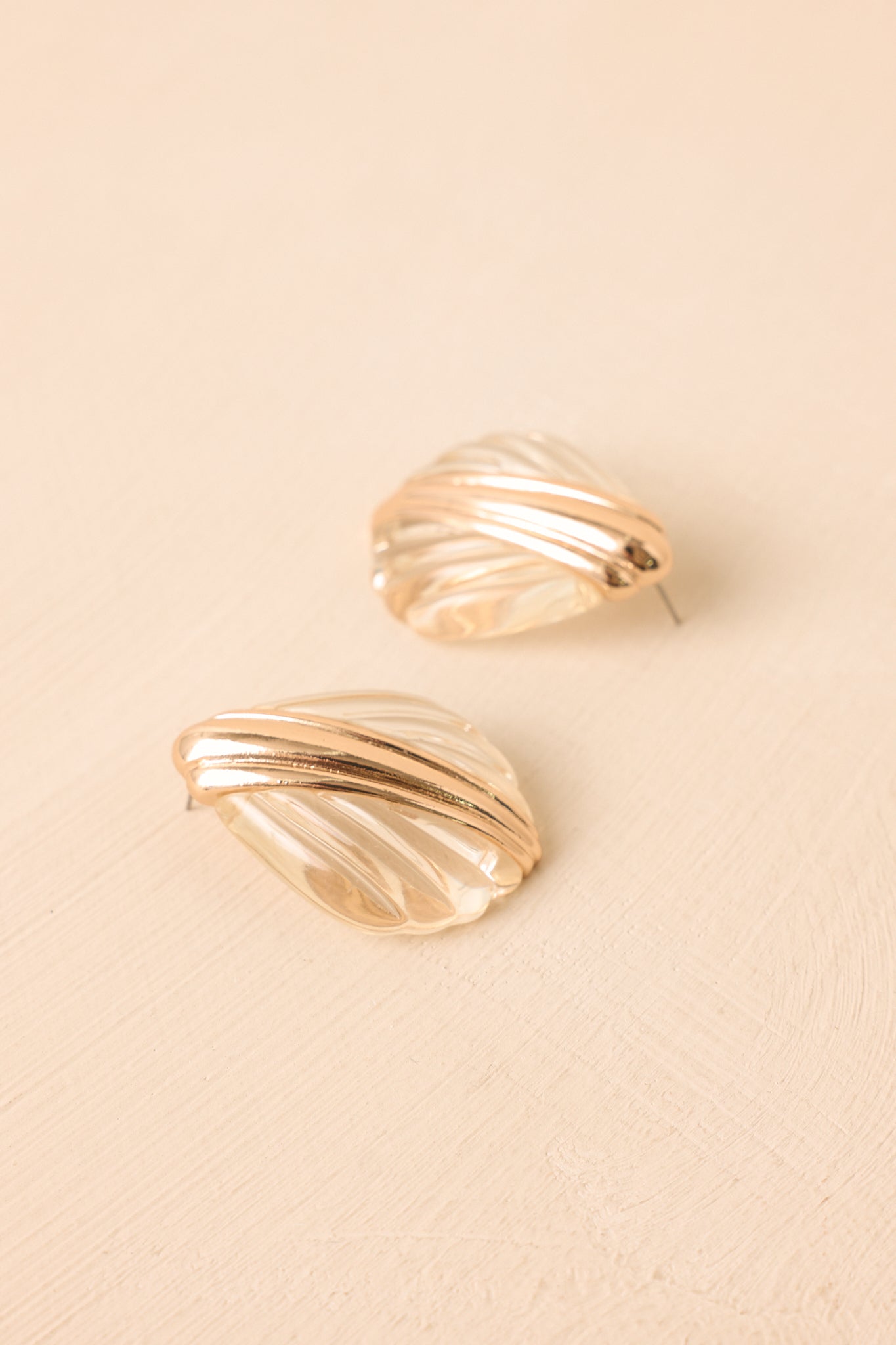Sculptural shell earrings showcasing translucent clear accents, gold-tone hardware, and a lightweight statement silhouette.