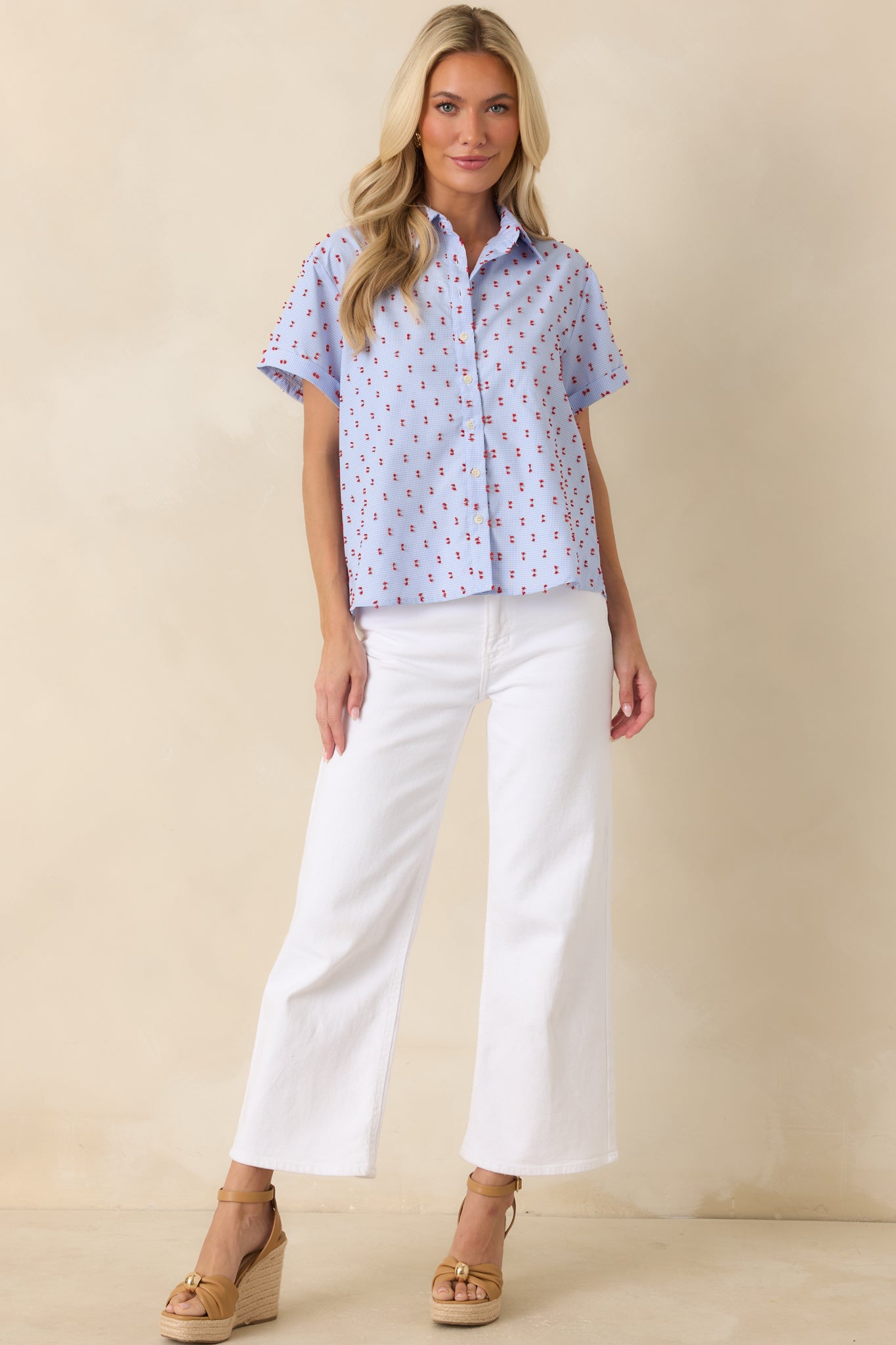 Relaxed-fit blue gingham top with a full button-front design and eye-catching red embroidered details.