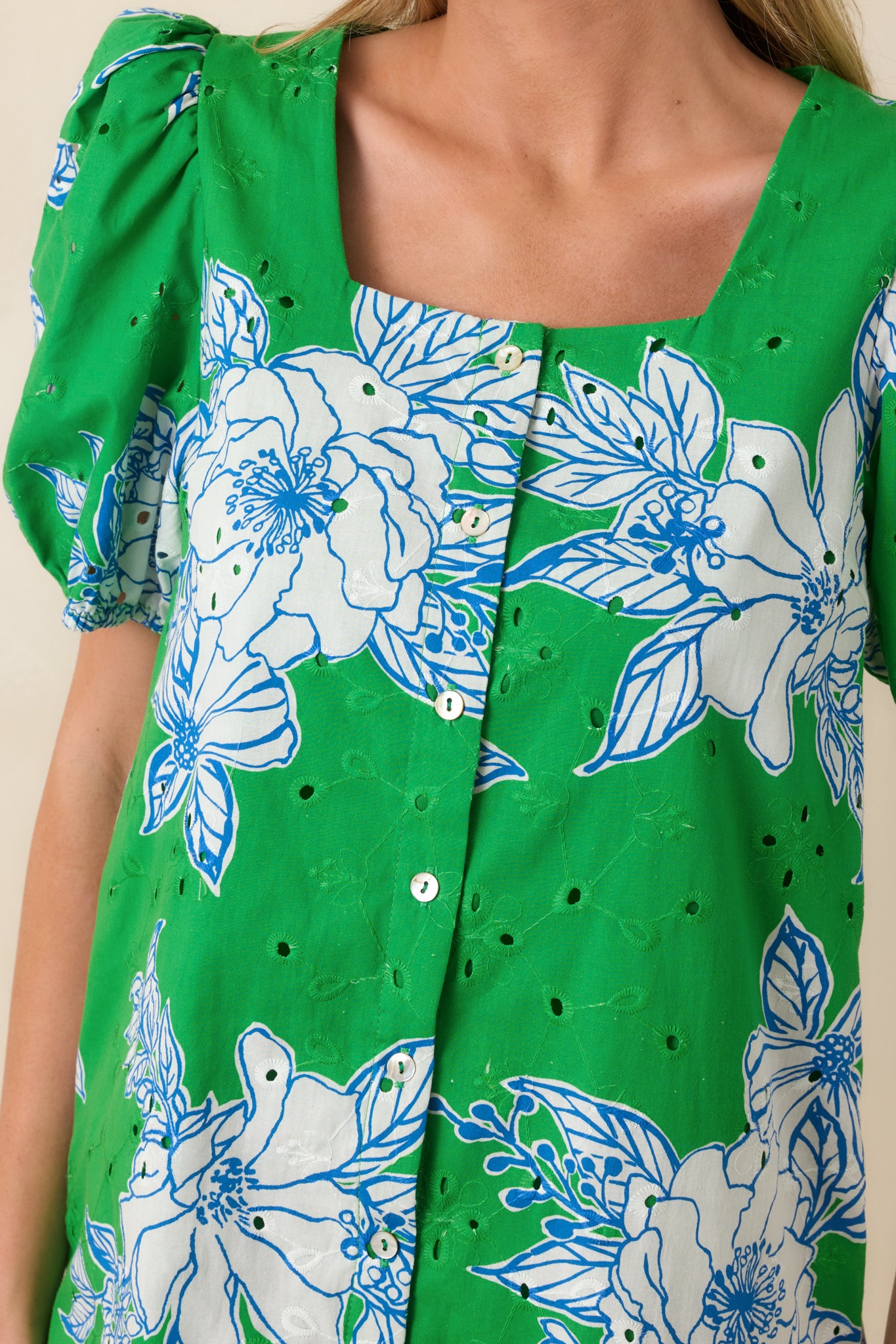 Detailed view of cotton eyelet fabric, floral print, and front button detailing on mini dress.