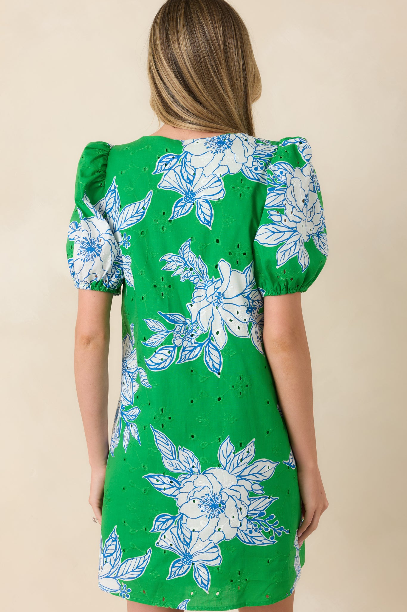 Rear view of green and white floral mini dress featuring puff sleeves and relaxed shift silhouette.

