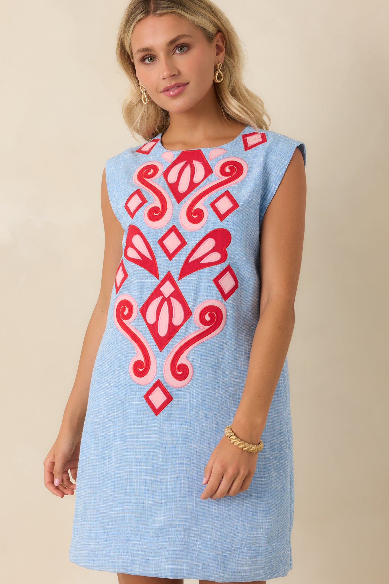 Heather blue shift dress featuring vibrant stitched appliqué accents and an easy relaxed drape.