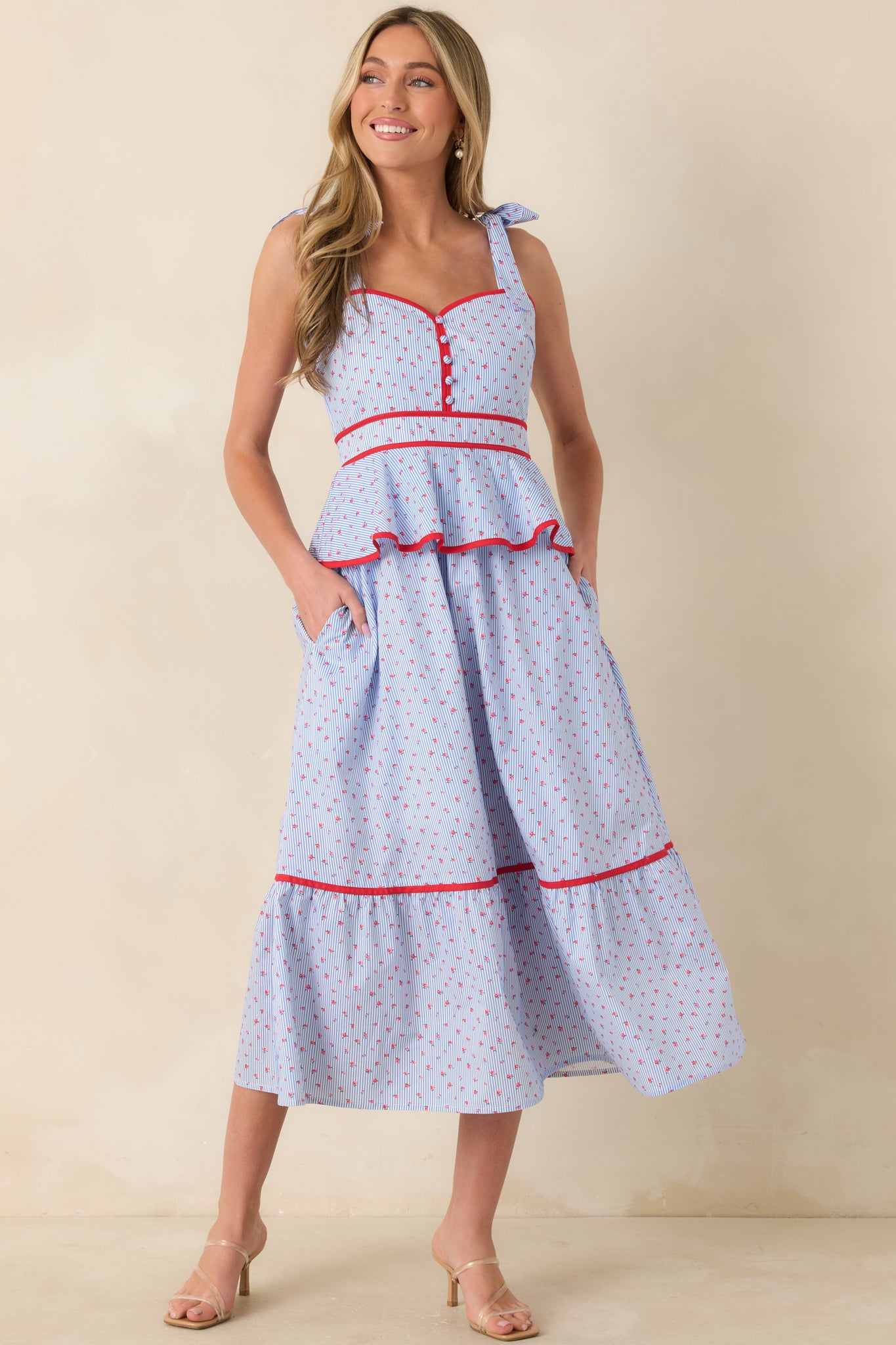 Light blue and red midi dress featuring a sweetheart neckline, tie straps, and decorative front buttons.
